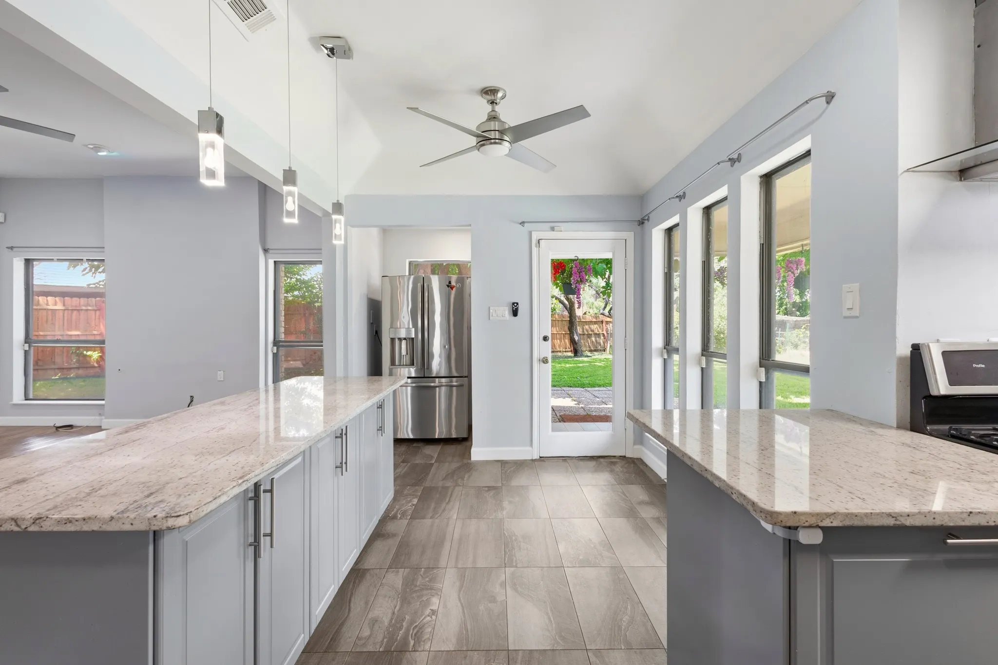 Open-concept kitchen featuring light-toned cabinetry, granite countertops, wood-finish flooring, and a vaulted ceiling with a ceiling fan