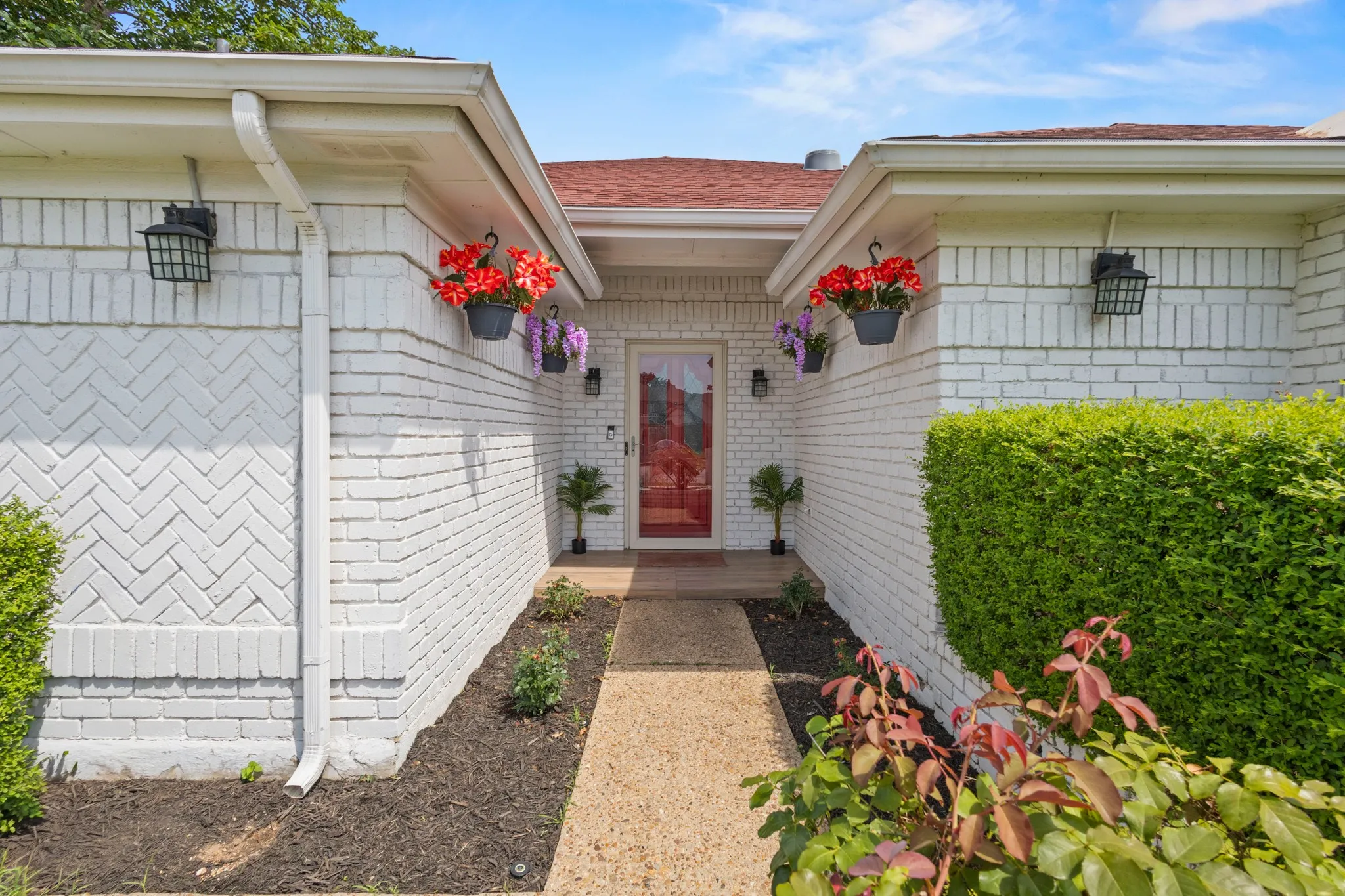 White painted brick exterior with a prominent red entry door