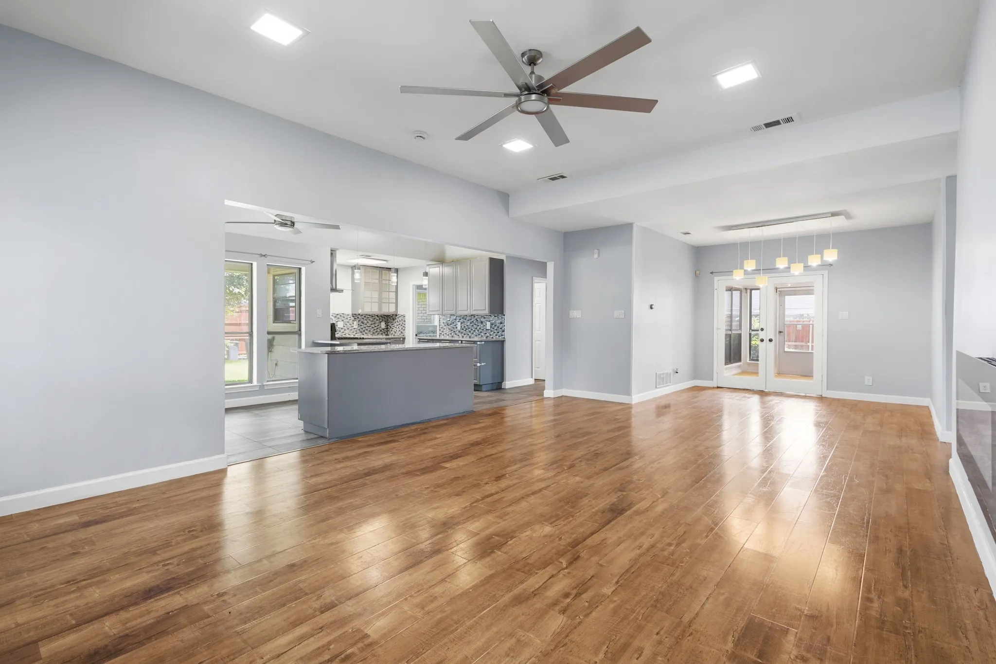 Expansive living area featuring wood-finish flooring, recessed lighting, and a ceiling fan