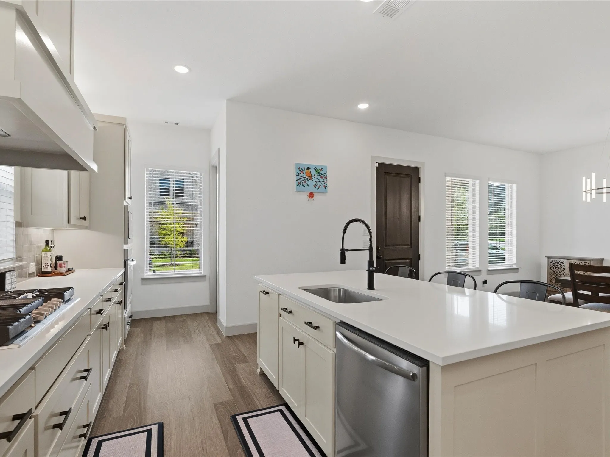 Modern kitchen featuring light-toned cabinetry, stainless steel appliances, and a central island with a sink and seating area