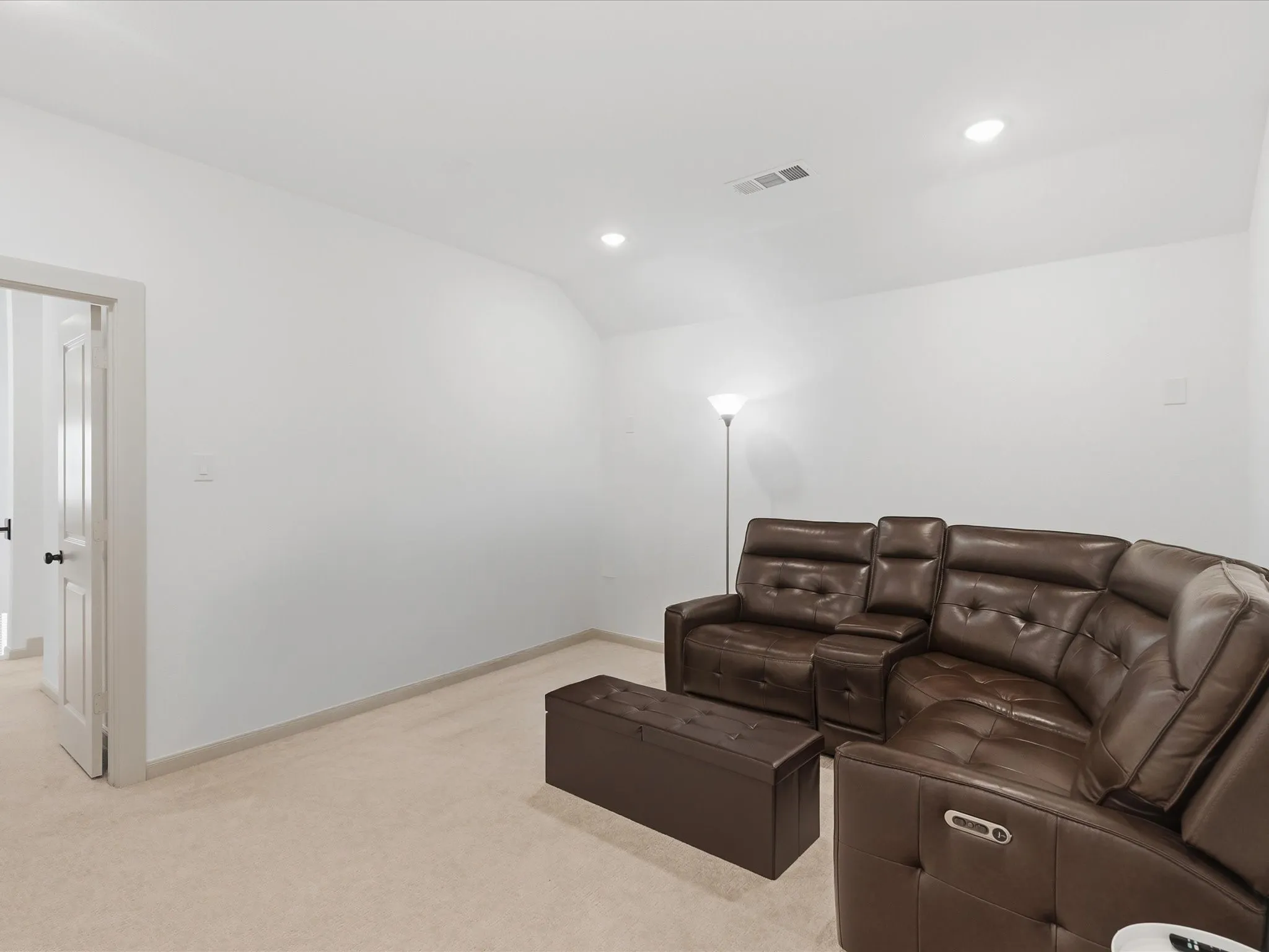 Carpeted room with recessed lighting and a white paneled door