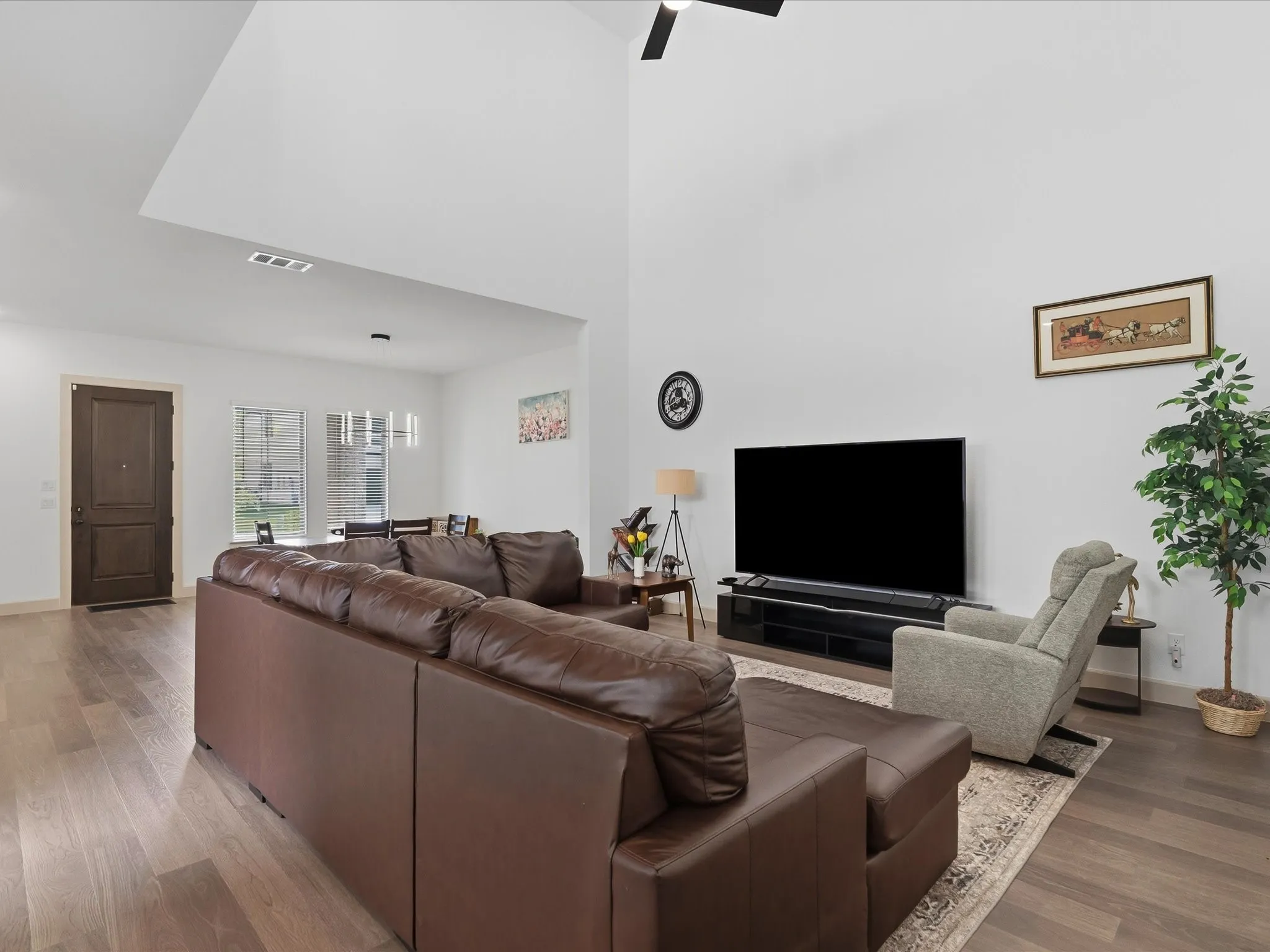 Spacious living area featuring high vaulted ceilings, wood-finish flooring, and a ceiling fan