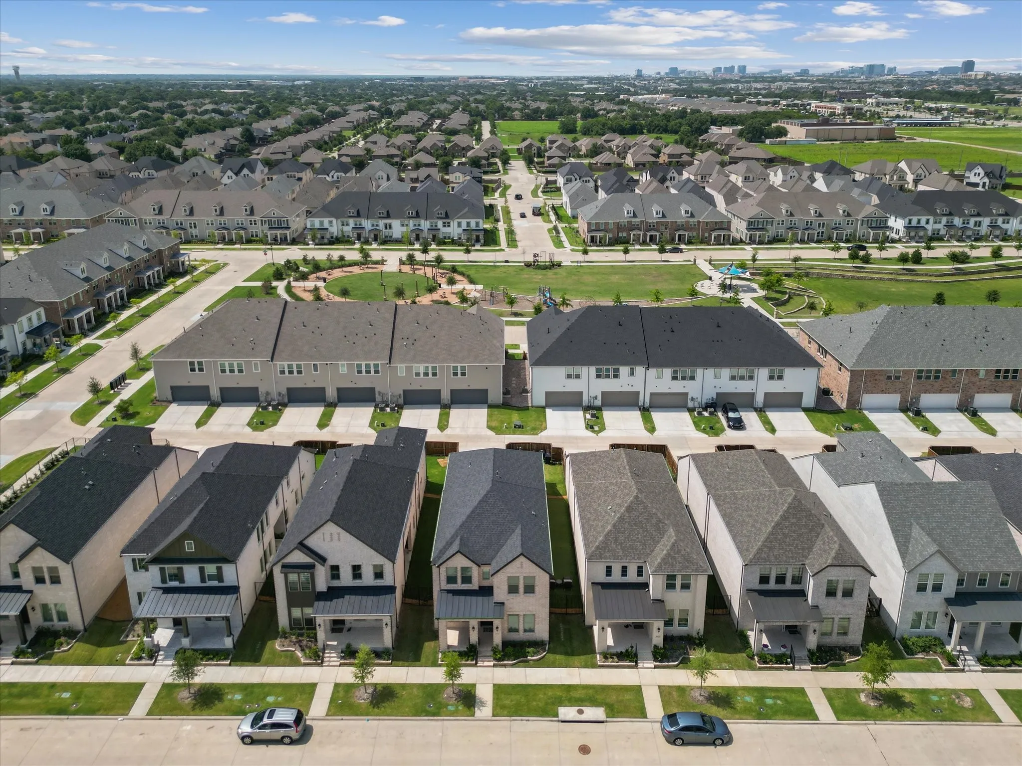Aerial overview of a residential development featuring varied architectural styles and a central green space with walking paths