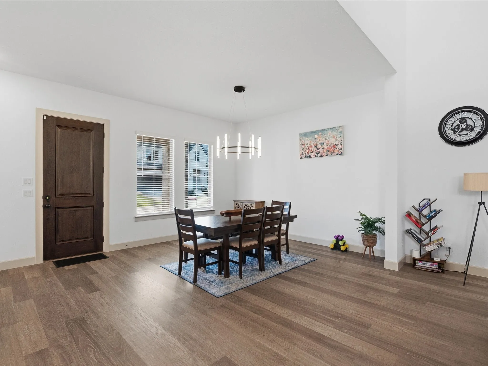 Dining area featuring wood-finish flooring, a contemporary linear chandelier, and ample natural light from two windows