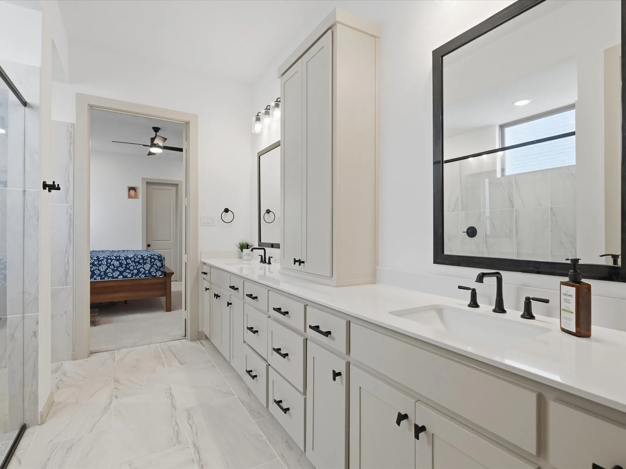 White bathroom cabinetry with matte black hardware and a built-in vertical storage cabinet