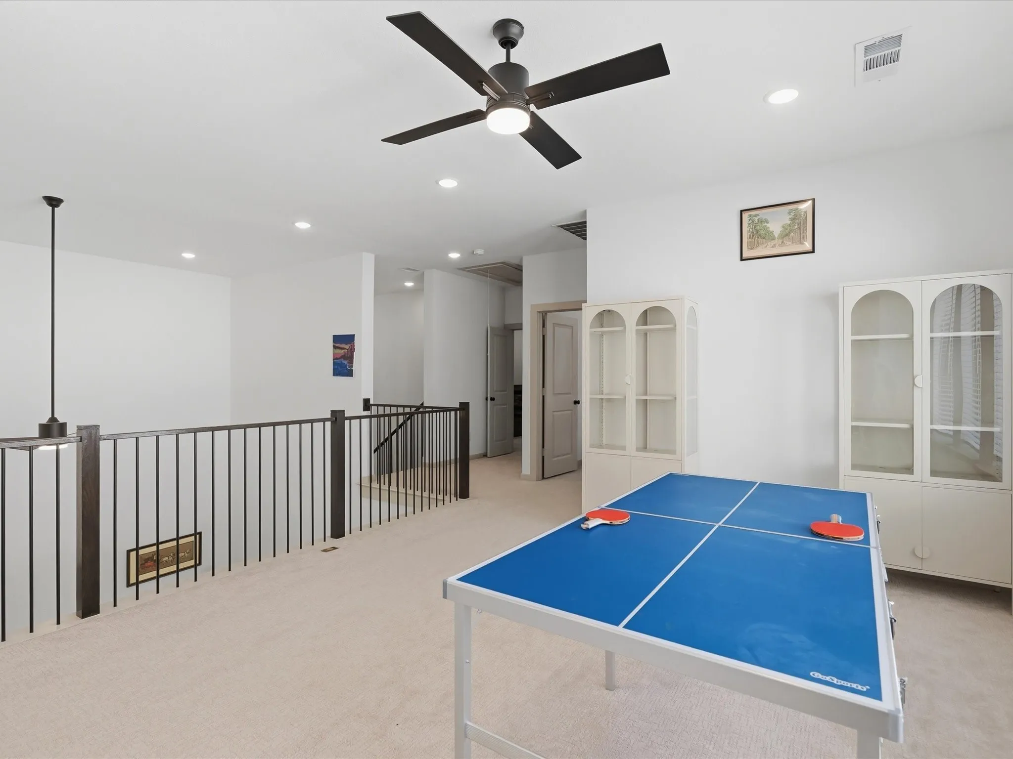Spacious loft area featuring light-colored carpeting and bright white walls