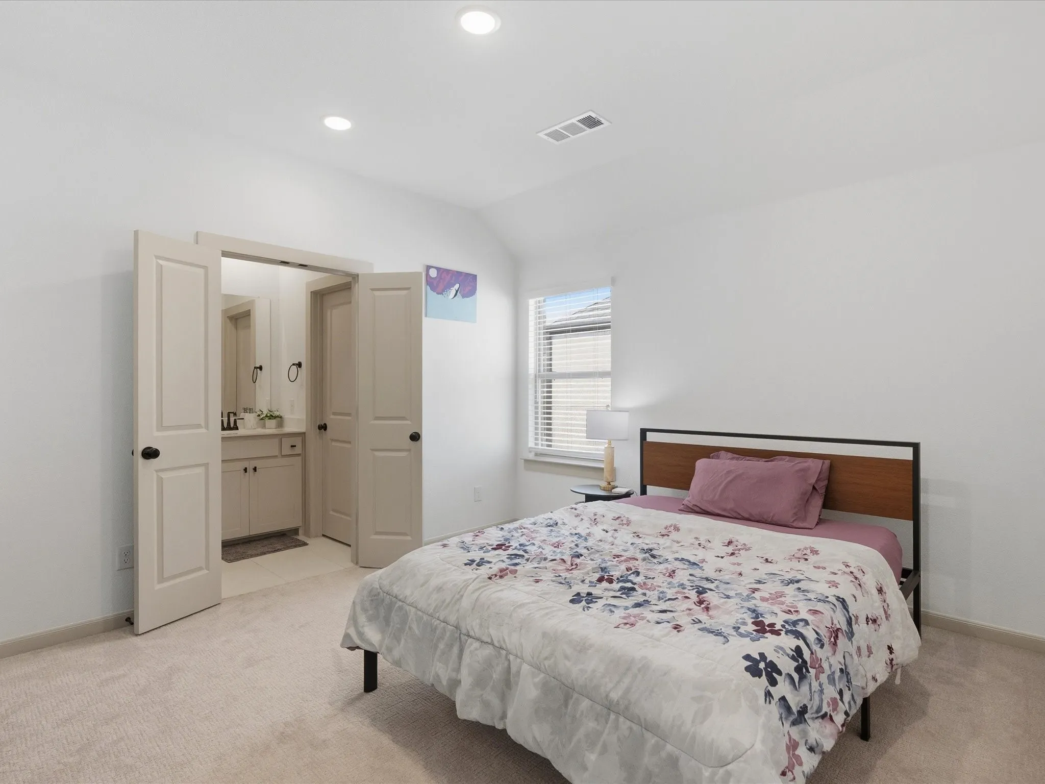 Bright bedroom featuring neutral carpeting, recessed lighting, and a window with blinds