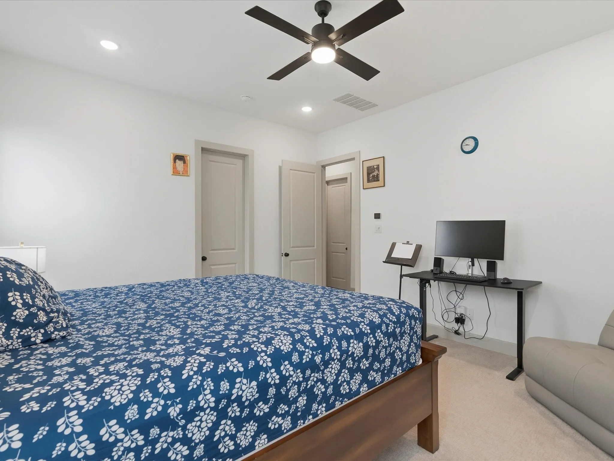 Recessed lighting illuminates this room featuring light-toned carpeting and a ceiling fan