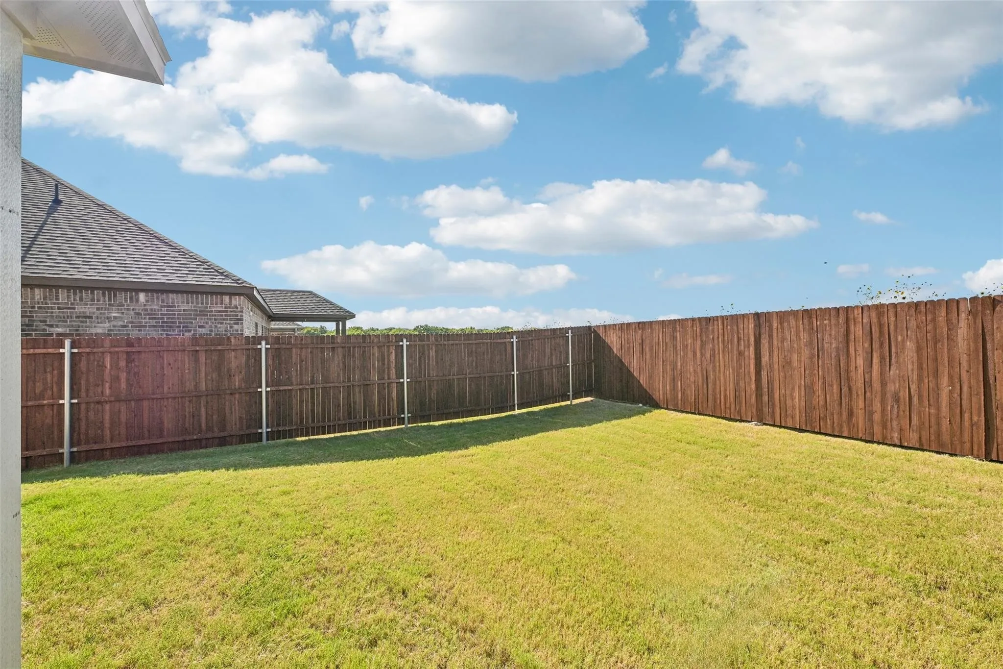 Expansive grassy yard enclosed by a wood privacy fence