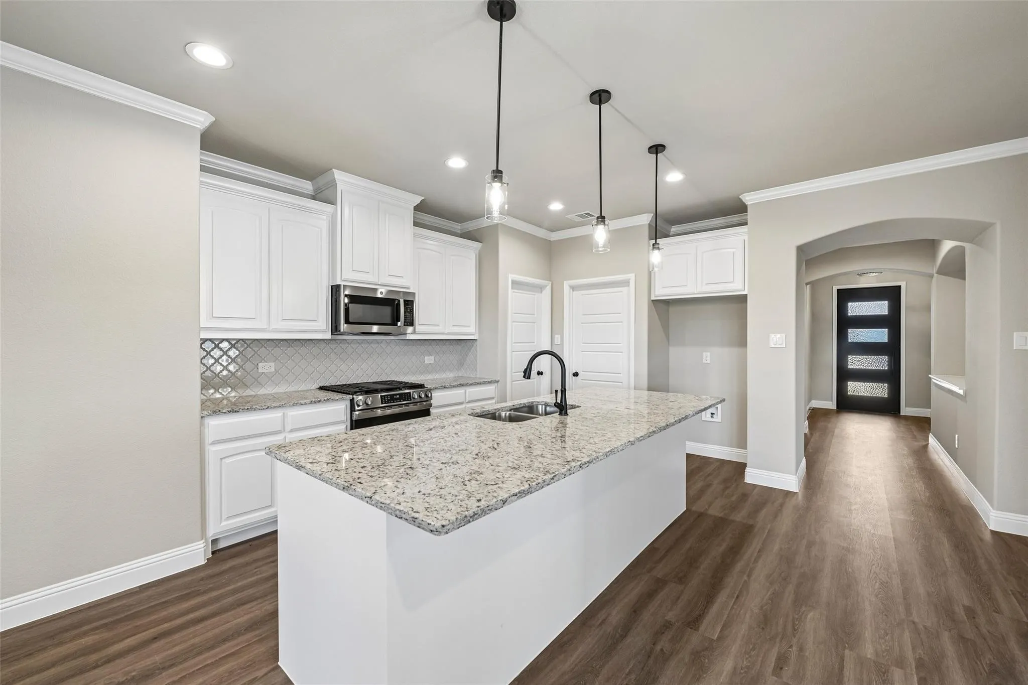 Kitchen featuring a central island with countertop seating, stainless steel appliances, white cabinetry, and wood-finish flooring