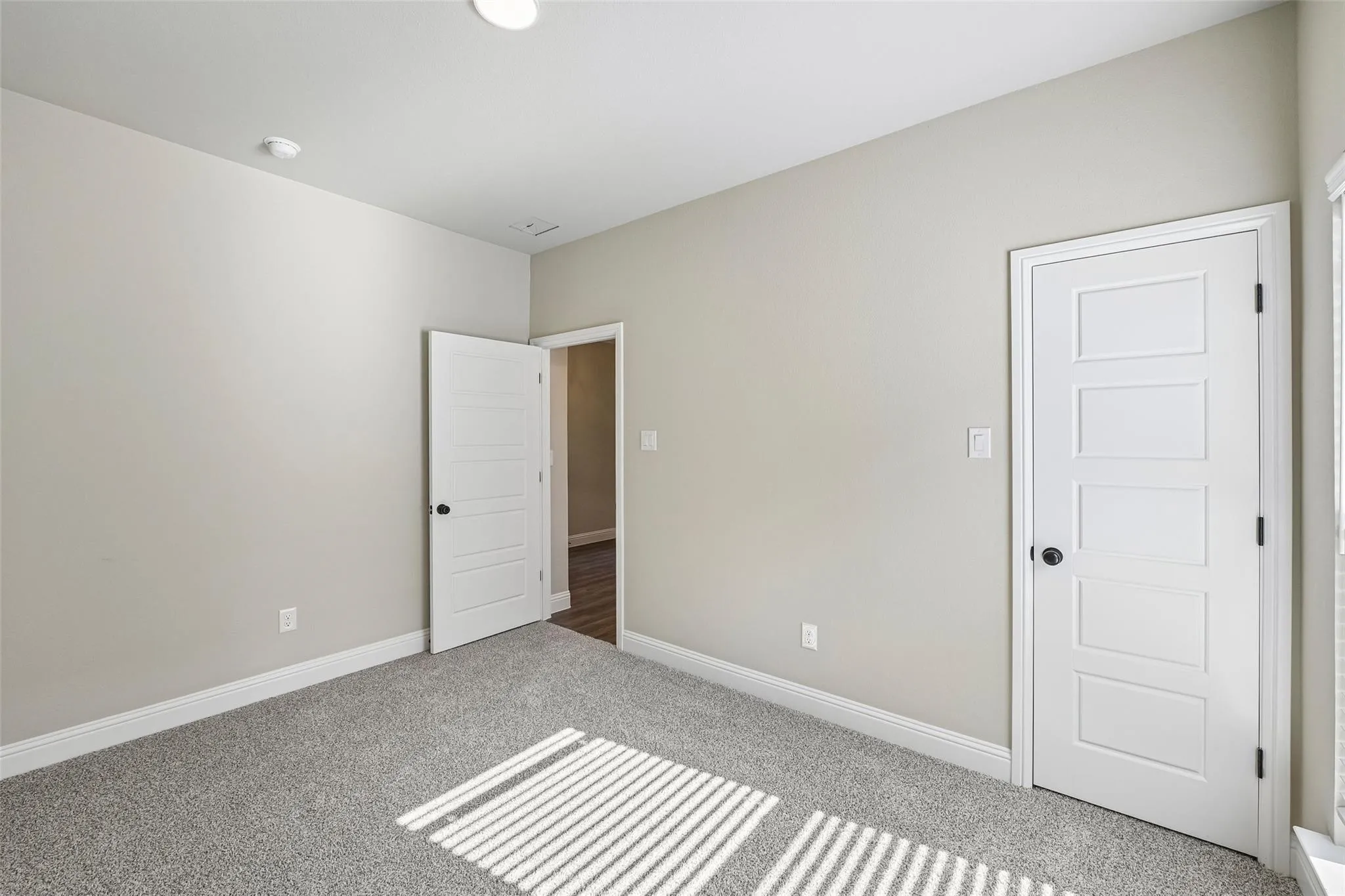 Neutral tone wall paint, plush carpeting, multi-panel interior doors with matte black hardware, and recessed ceiling lighting
