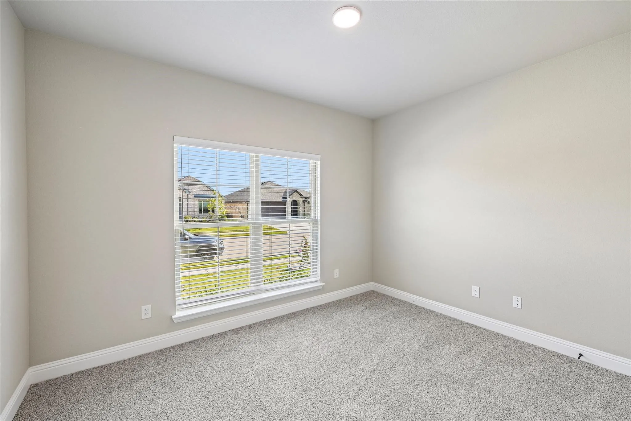 Recessed lighting, wall-to-wall carpeting, and a large window with blinds