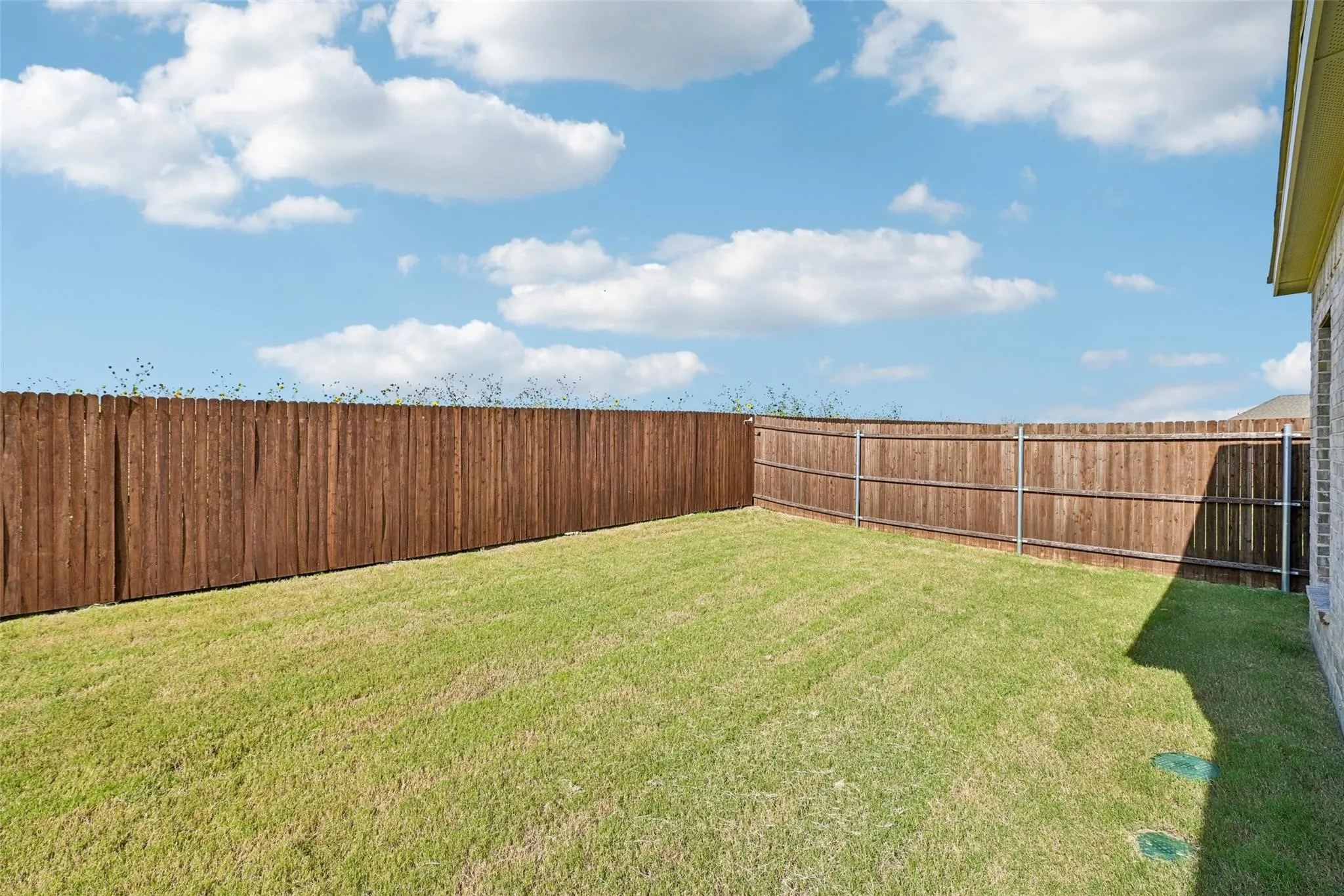 Expansive backyard featuring a manicured lawn and privacy fencing