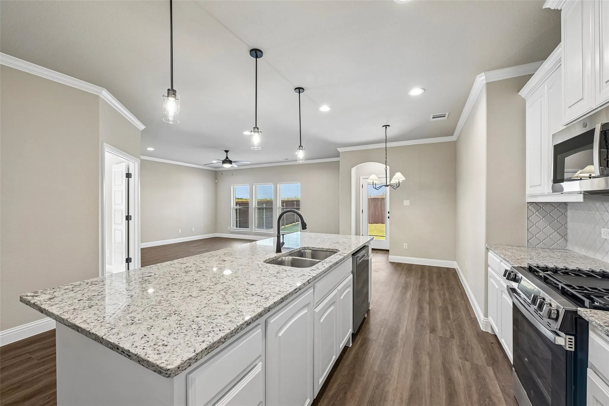 Kitchen island with light-toned countertop, stainless steel double sink, and pendant lighting