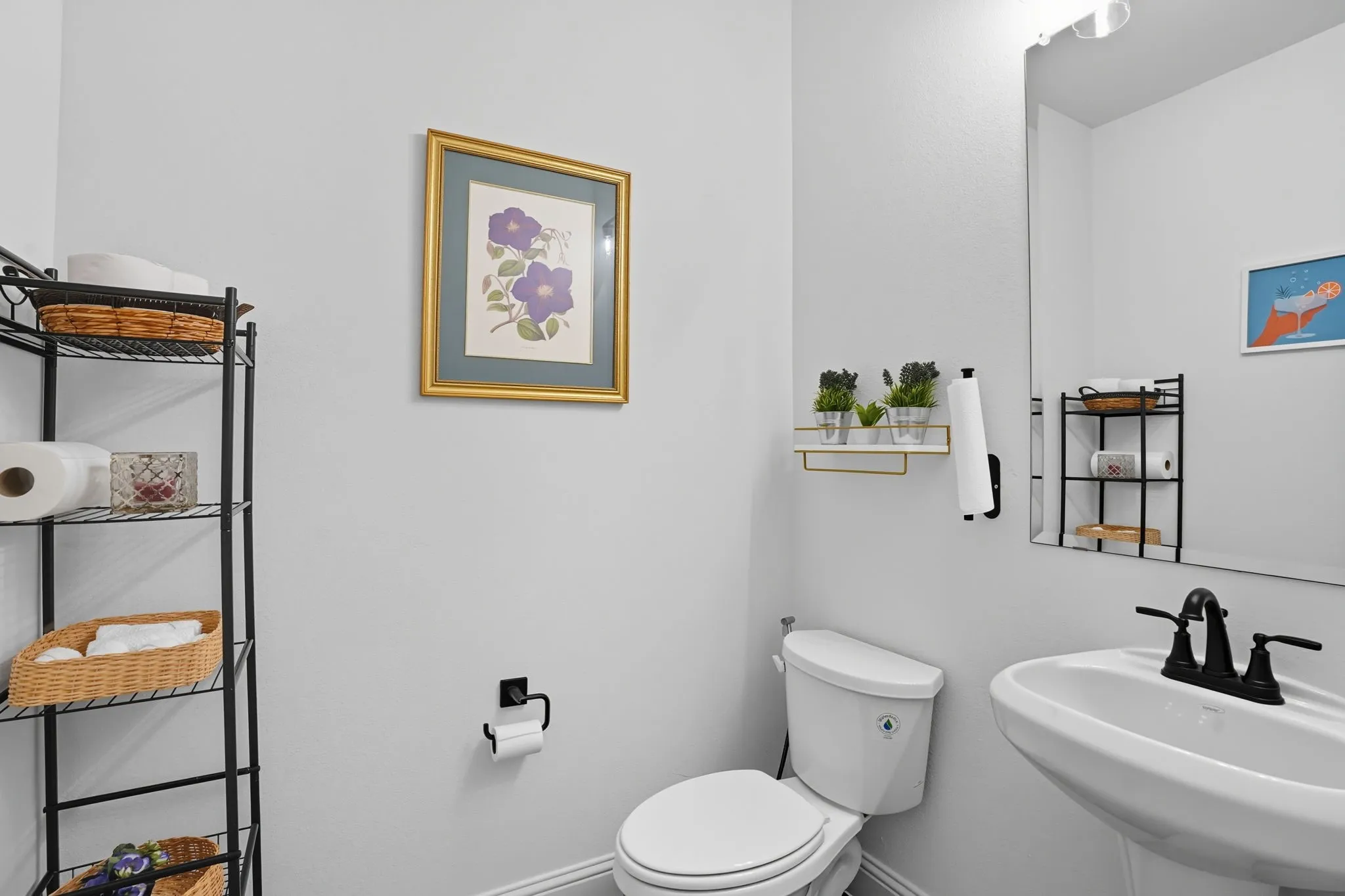Pedestal sink featuring a matte black faucet, wall-mounted mirror, and overhead lighting