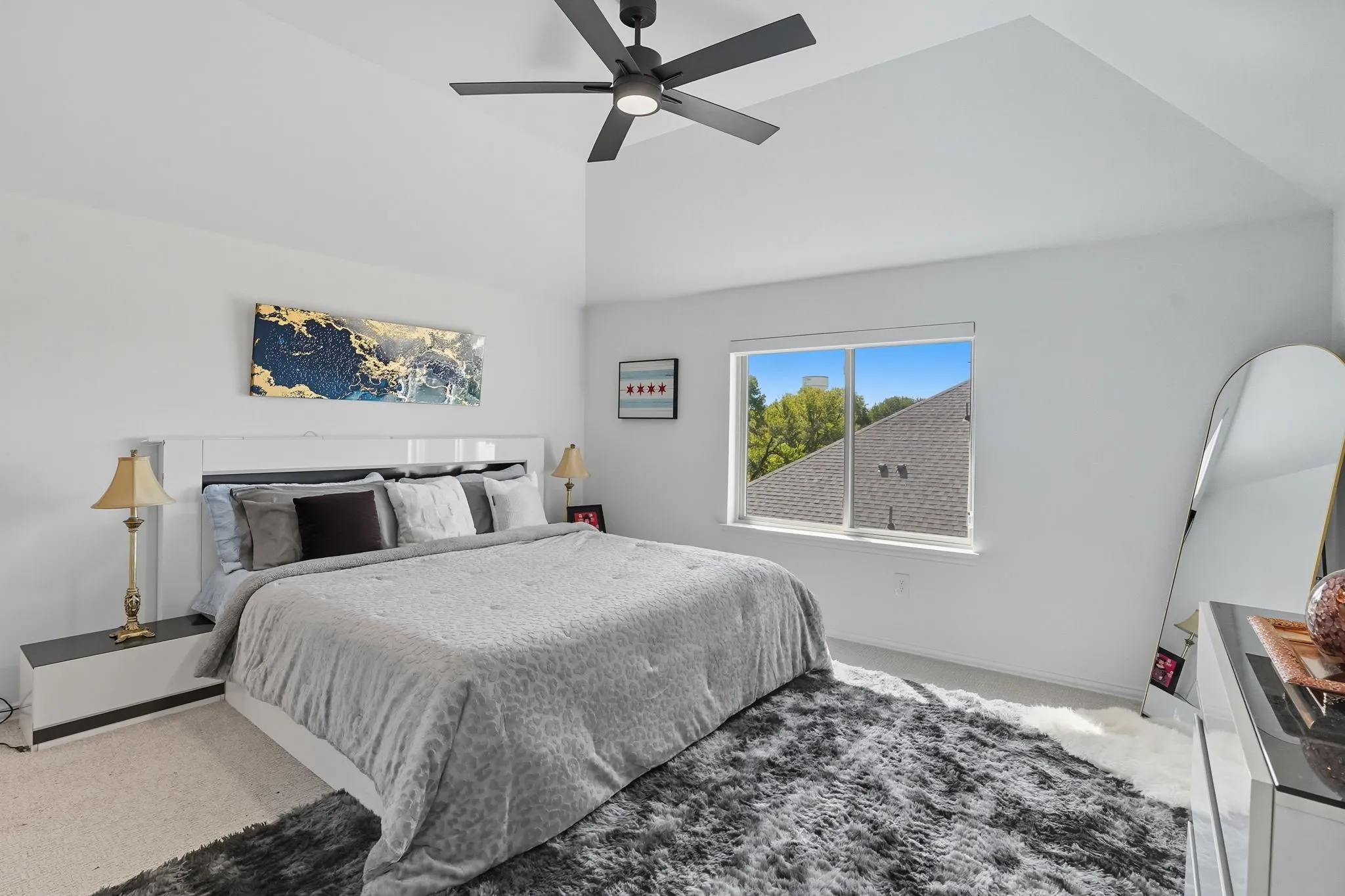Spacious bedroom featuring vaulted ceilings, a contemporary ceiling fan, and a large window providing natural light