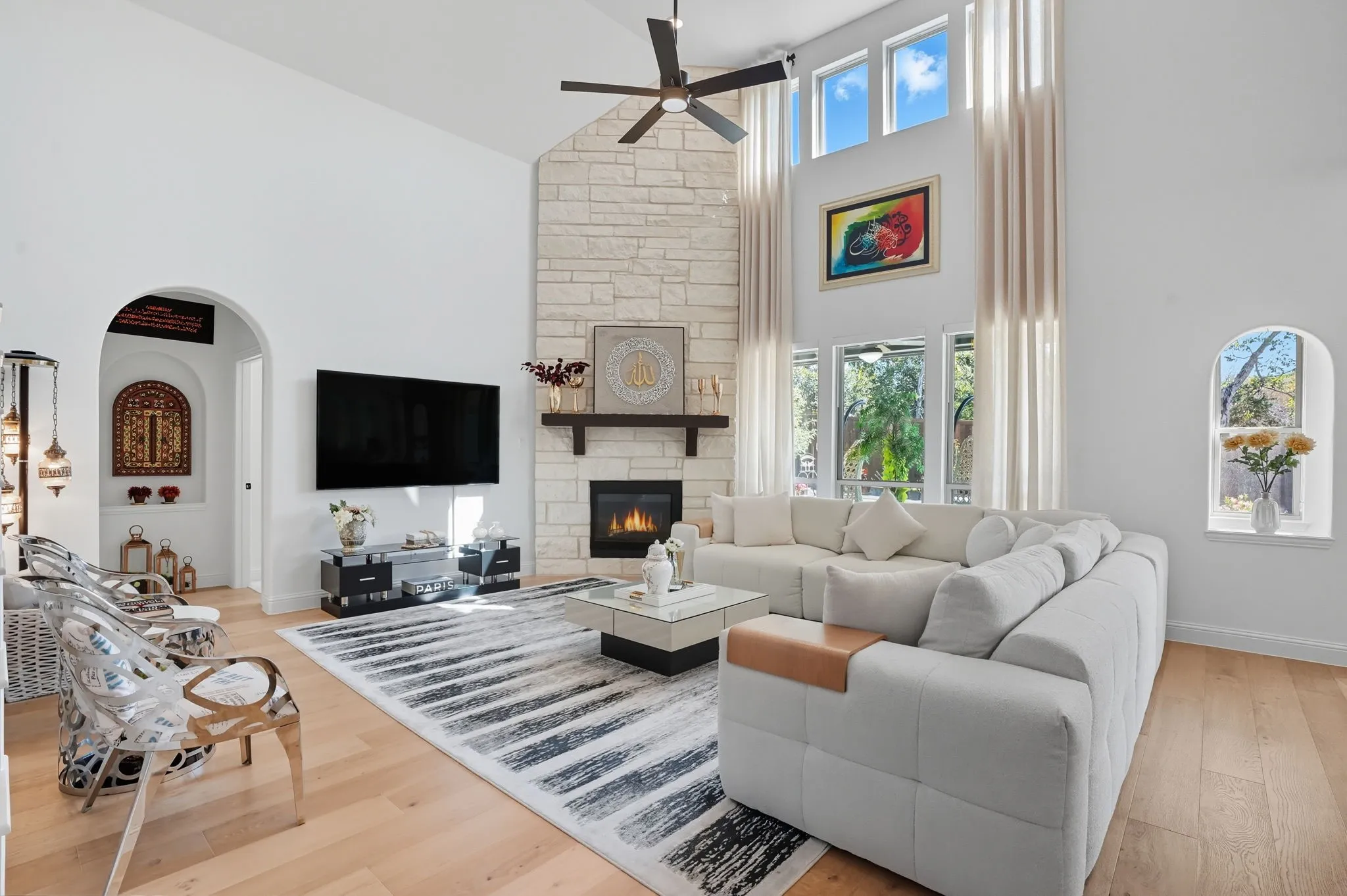 Spacious living room featuring vaulted ceilings, a floor-to-ceiling stone fireplace, and wood-finish flooring