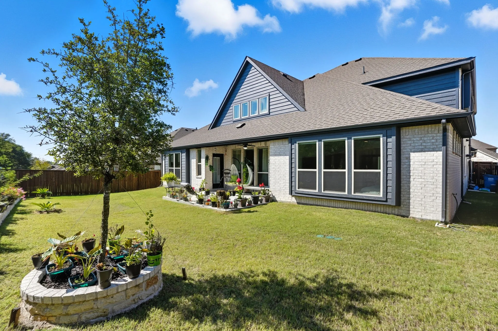 Expansive backyard featuring a manicured lawn and a substantial brick and siding exterior