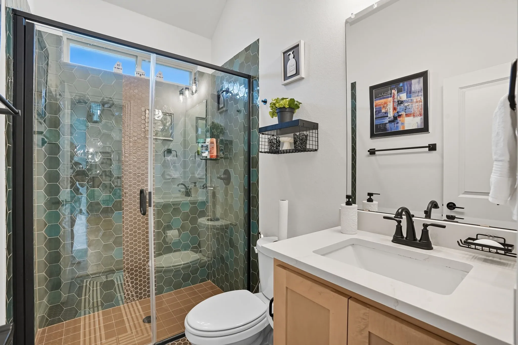 Full bathroom featuring a walk-in shower with hexagonal wall tile and contrasting floor tile, a single vanity with a quartz-finish countertop, and a recessed panel vanity cabinet