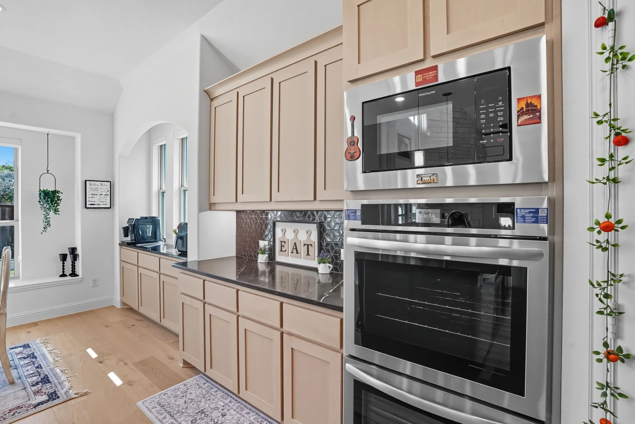 Kitchen featuring light wood-finish cabinetry, dark countertops, and a decorative tile backsplash