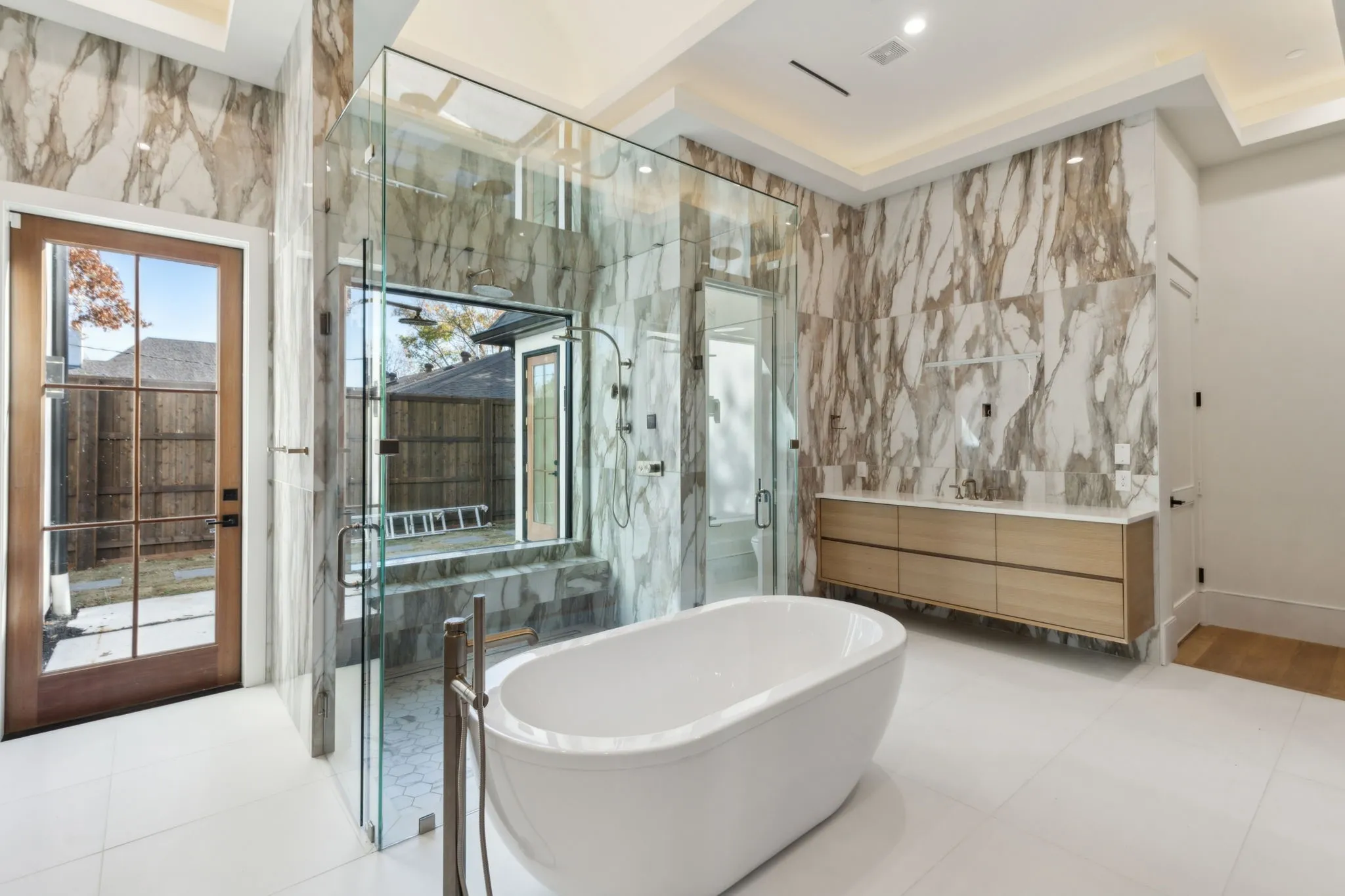 Full bathroom with tile walls, a freestanding bath, vanity, a marble finish shower, and light tile patterned flooring