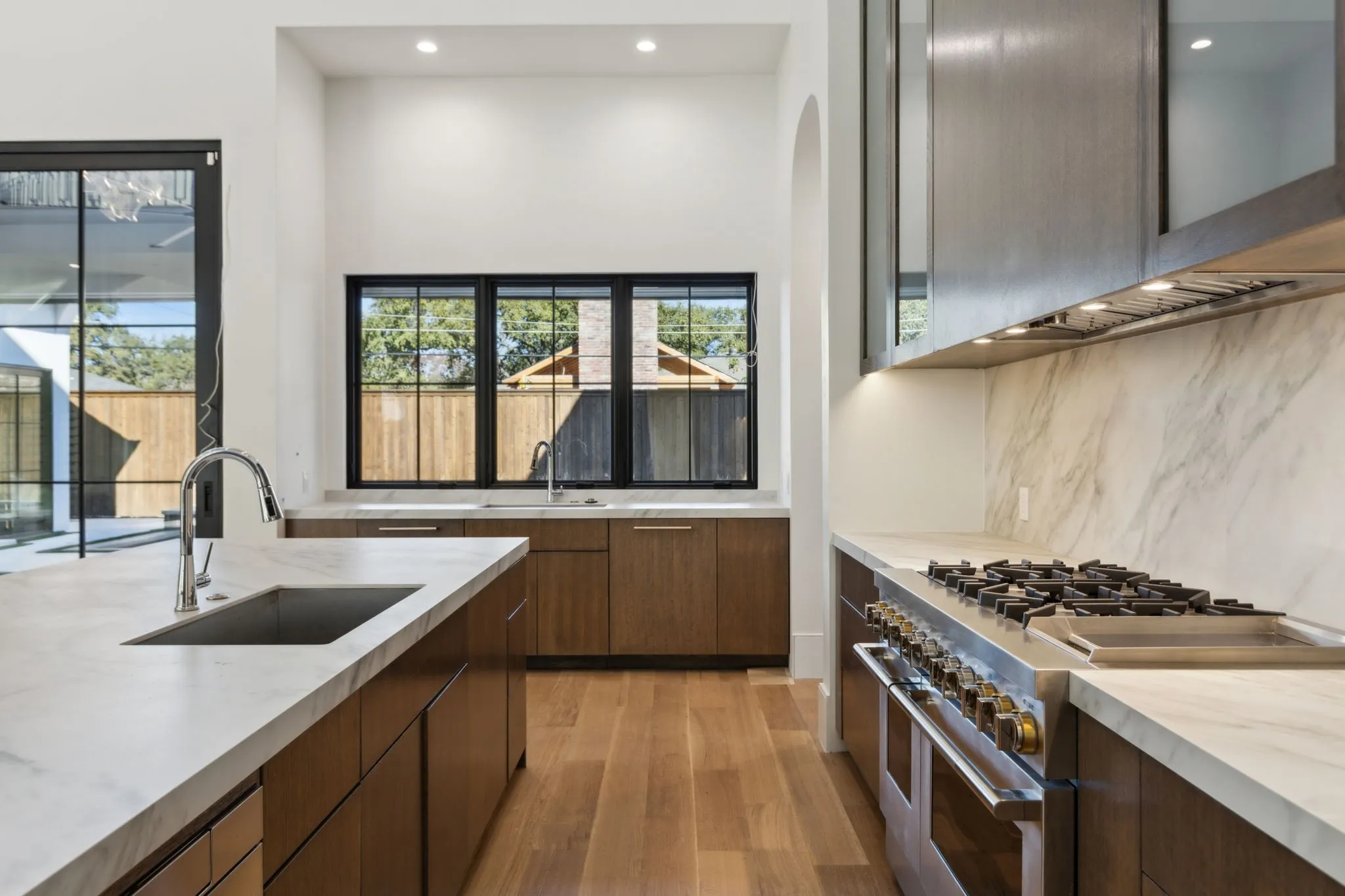 Kitchen featuring range with two ovens, light wood-style floors, modern cabinets, recessed lighting, and decorative backsplash