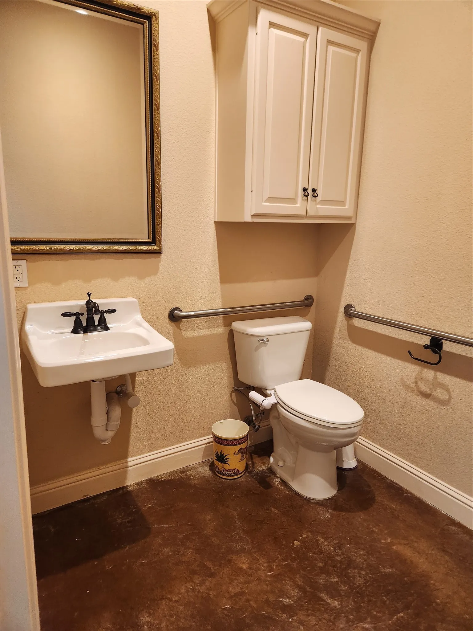 Bathroom featuring a wall-mounted sink with black fixtures, a white toilet, and a framed mirror