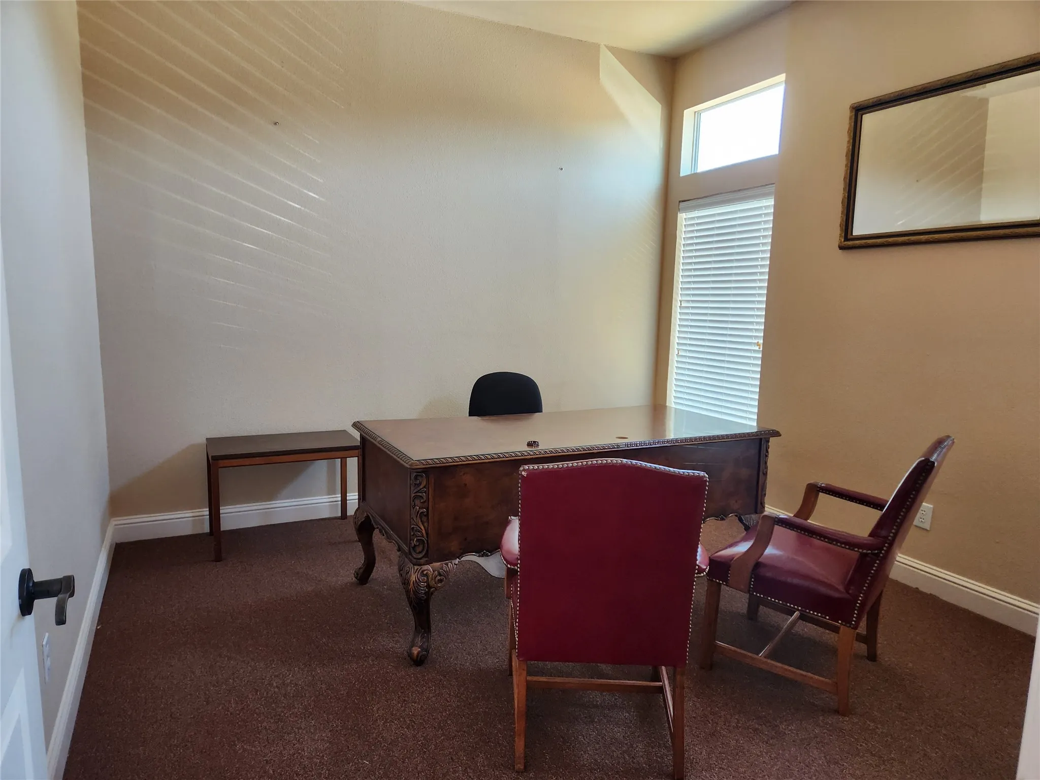 Carpeted room featuring a decorative wood desk, crown molding, and a transom window