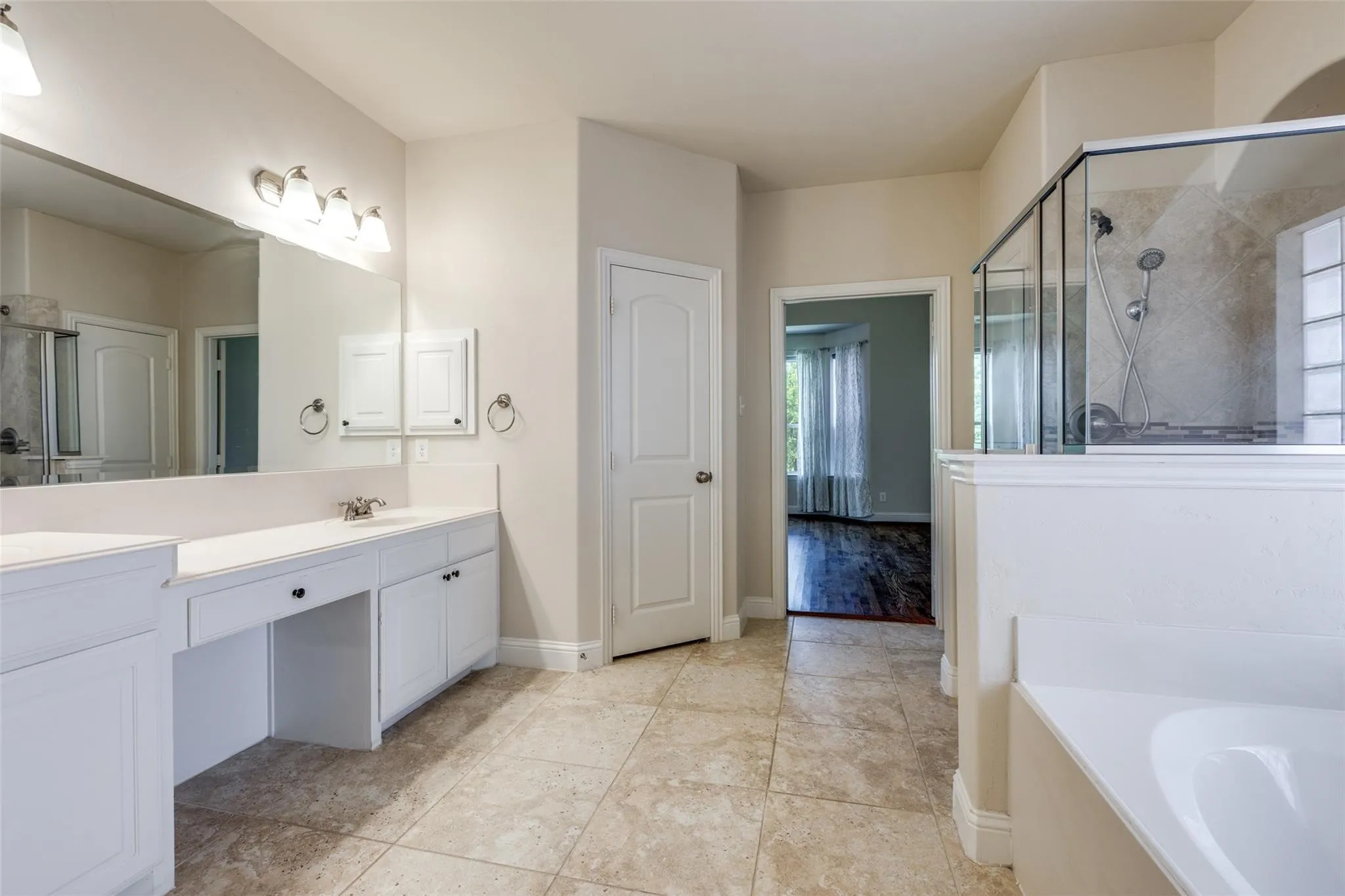 Bathroom featuring a dual vanity with white cabinetry, a built-in makeup area, and a large mirror