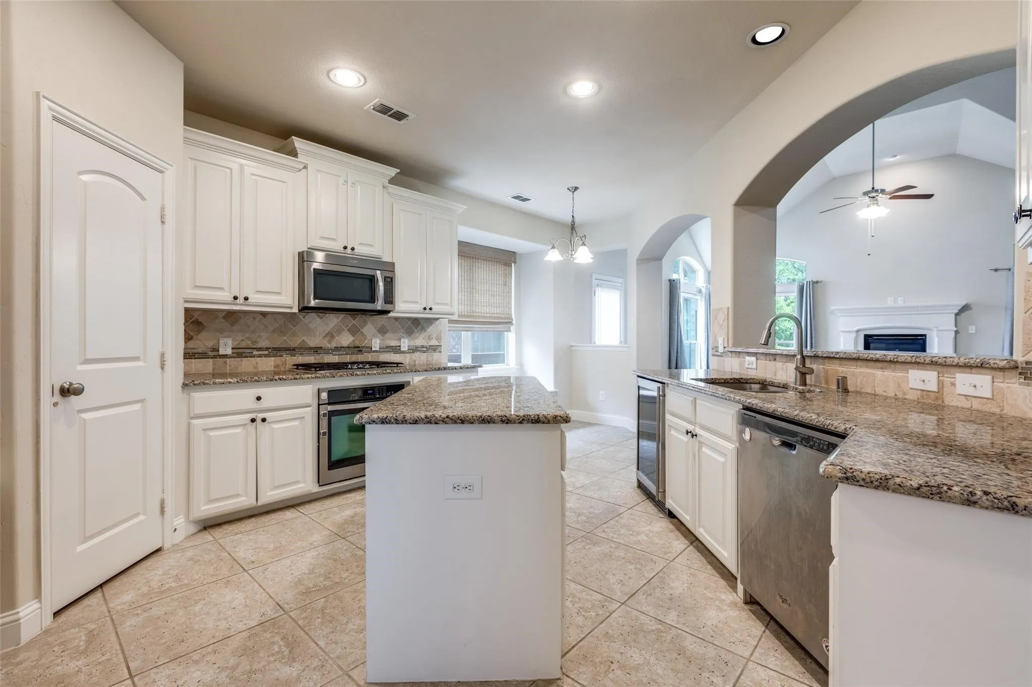 Modern kitchen featuring white cabinetry, granite countertops, stainless steel appliances, a tiled backsplash, and recessed lighting
