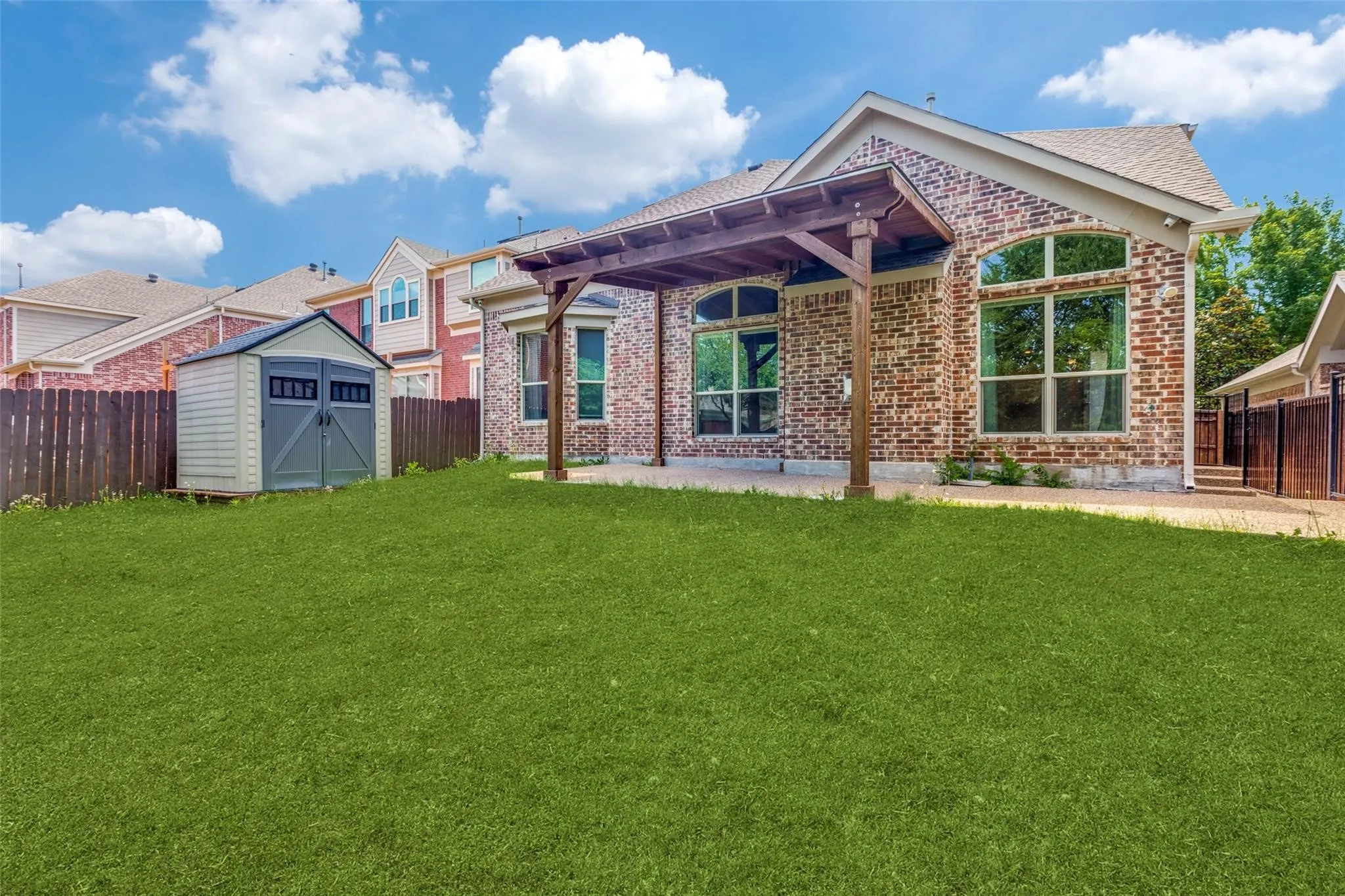 Rear brick elevation with an attached wooden pergola over a concrete patio
