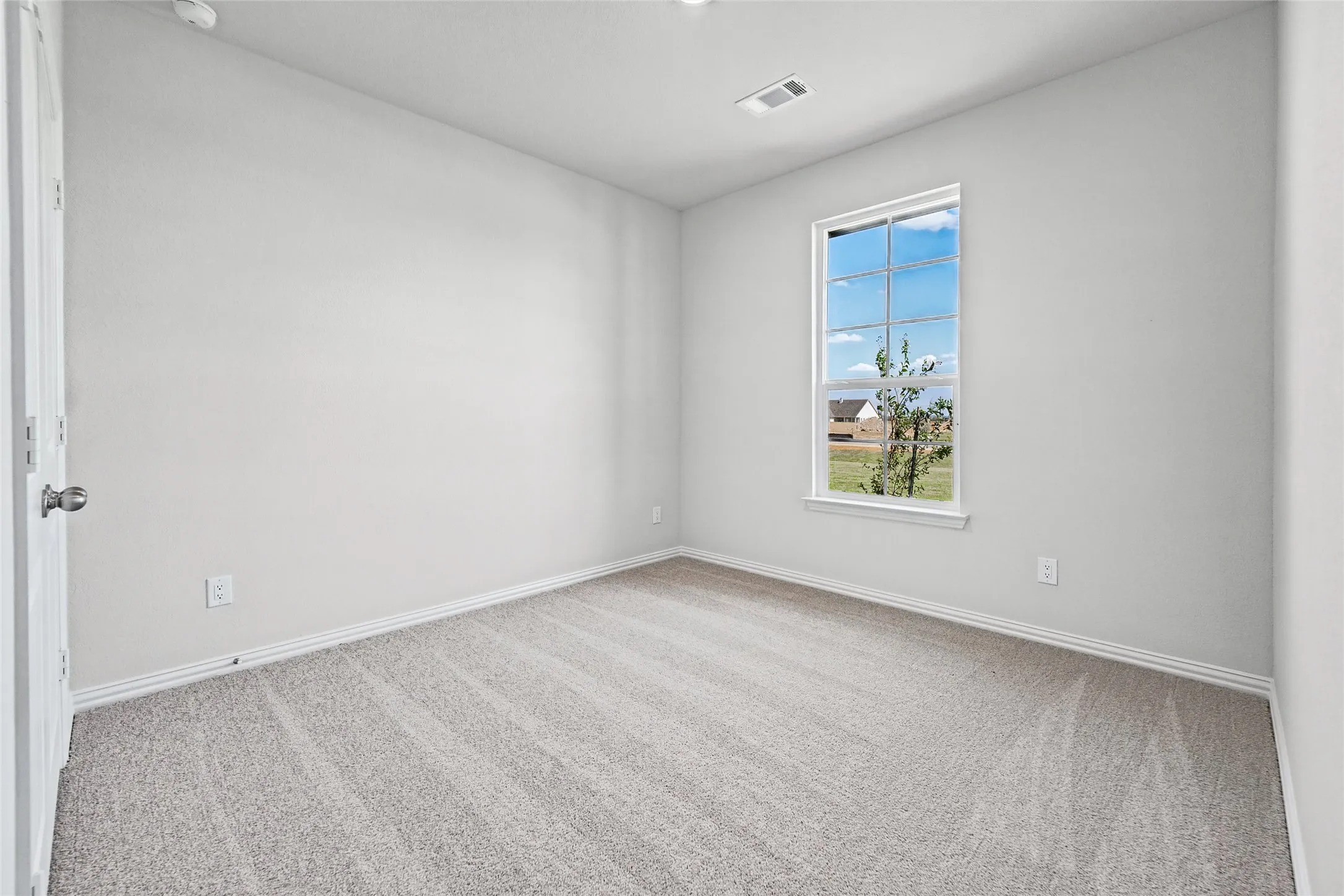 Neutral-toned carpeting with white trim, a single window, and light-colored walls