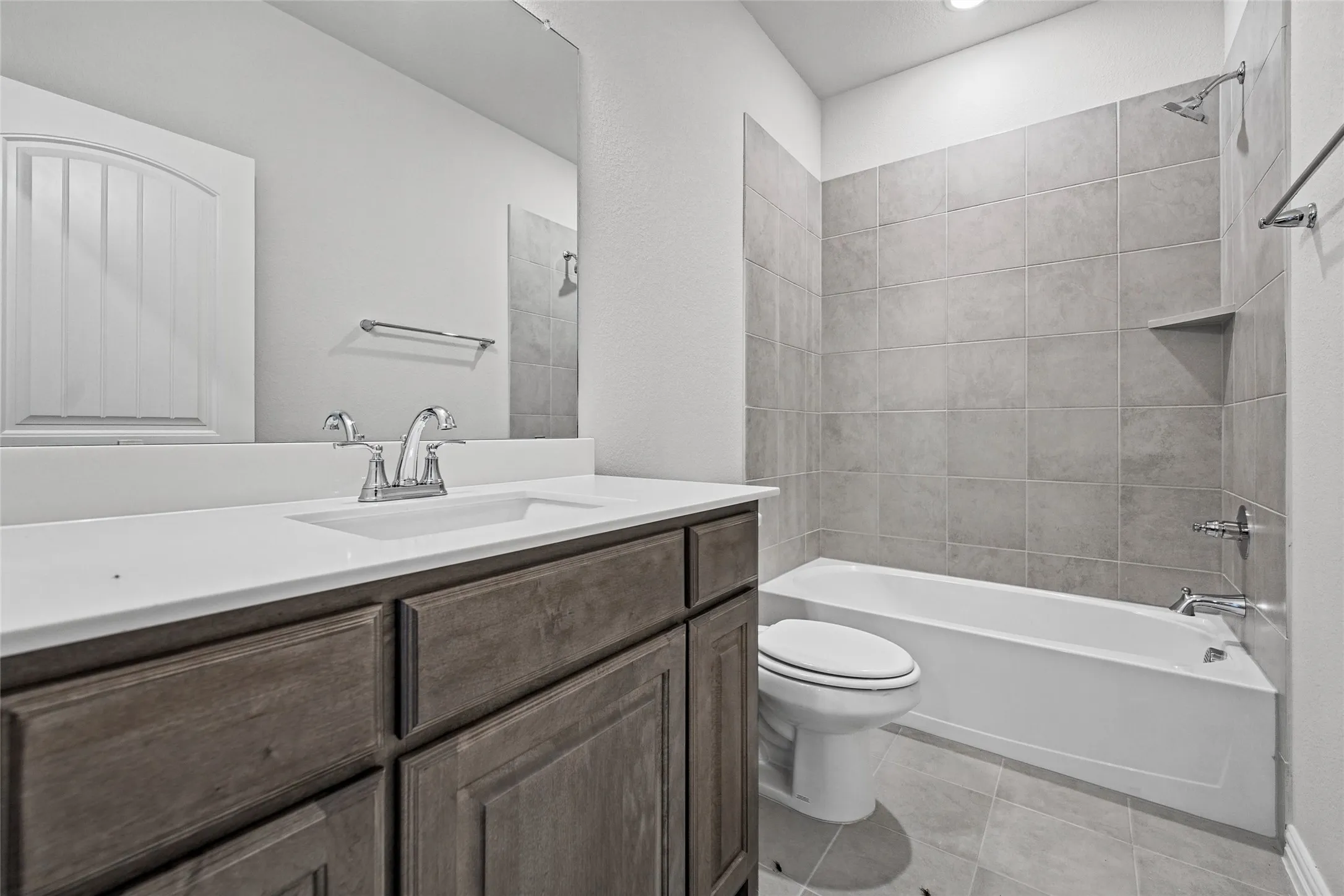 Vanity with a white countertop and integrated sink, chrome faucet, wood-finish cabinetry, and a full-width mirror