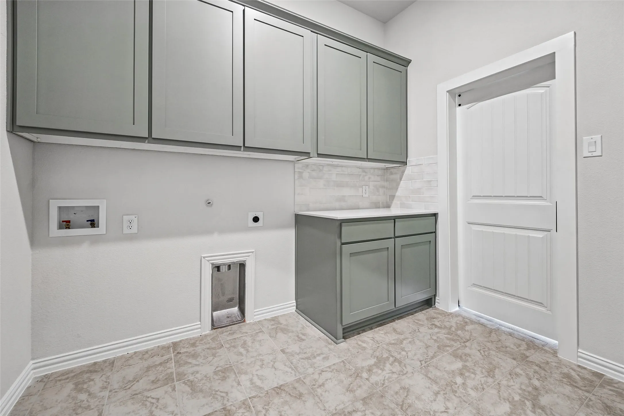 Spacious utility room featuring gray cabinetry, a white countertop, and light-toned tile flooring