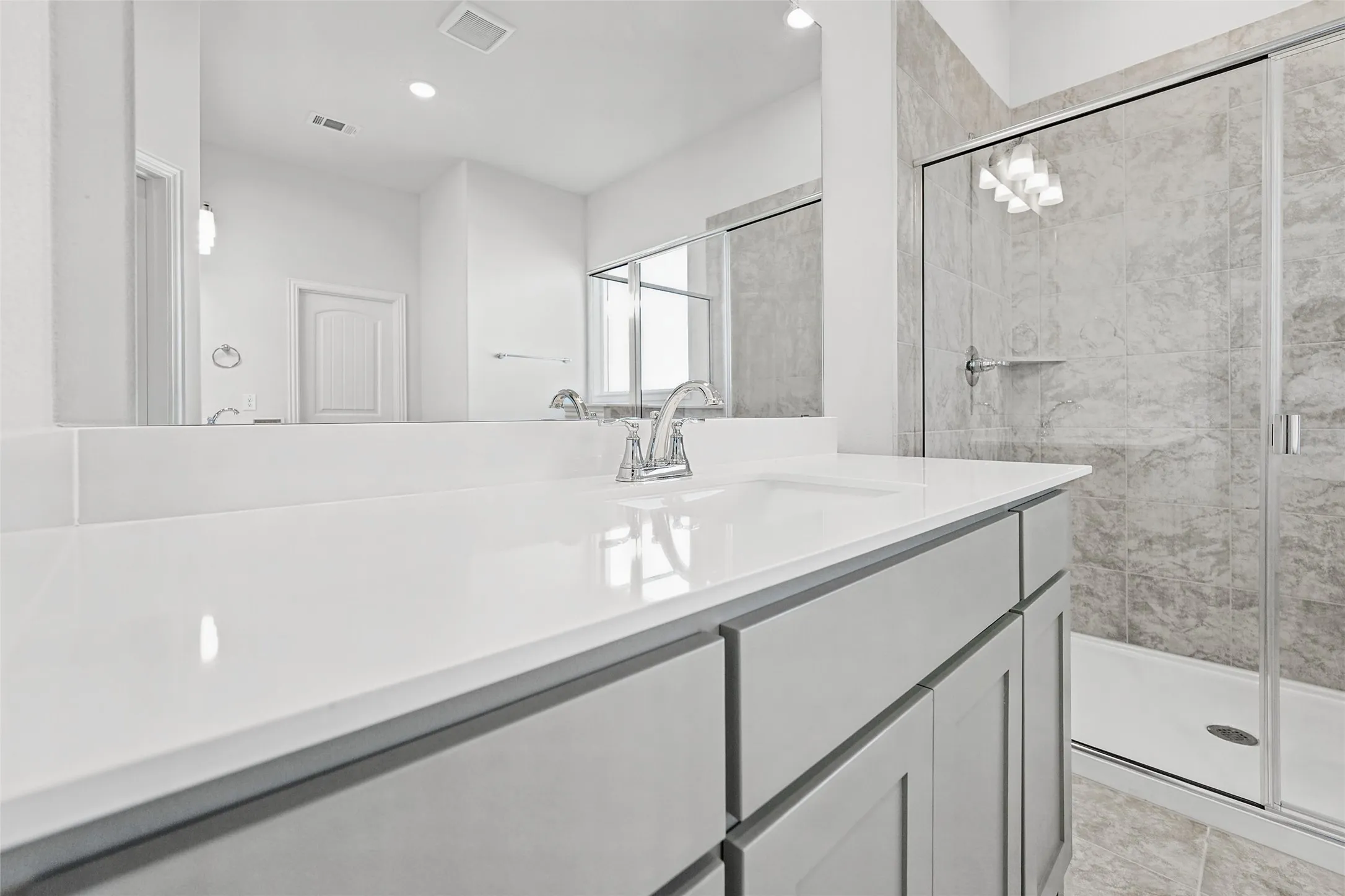 Spacious vanity with a white solid surface countertop, undermount sink, and chrome faucet
