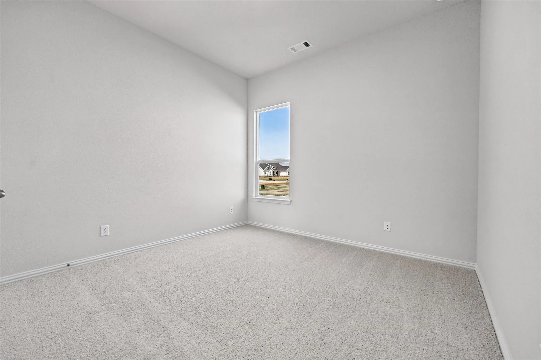 Carpeted room with a single window and light-colored walls