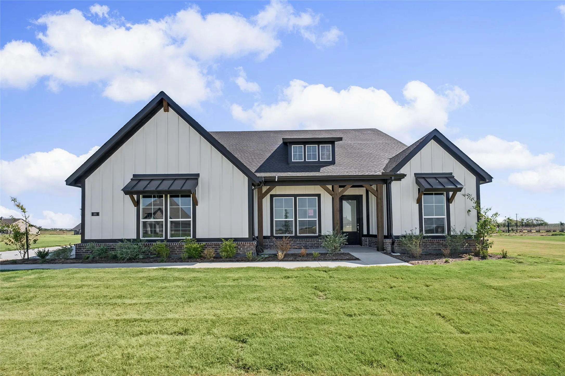 Modern farmhouse exterior with white board-and-batten siding, dark trim, and a dark shingled roof