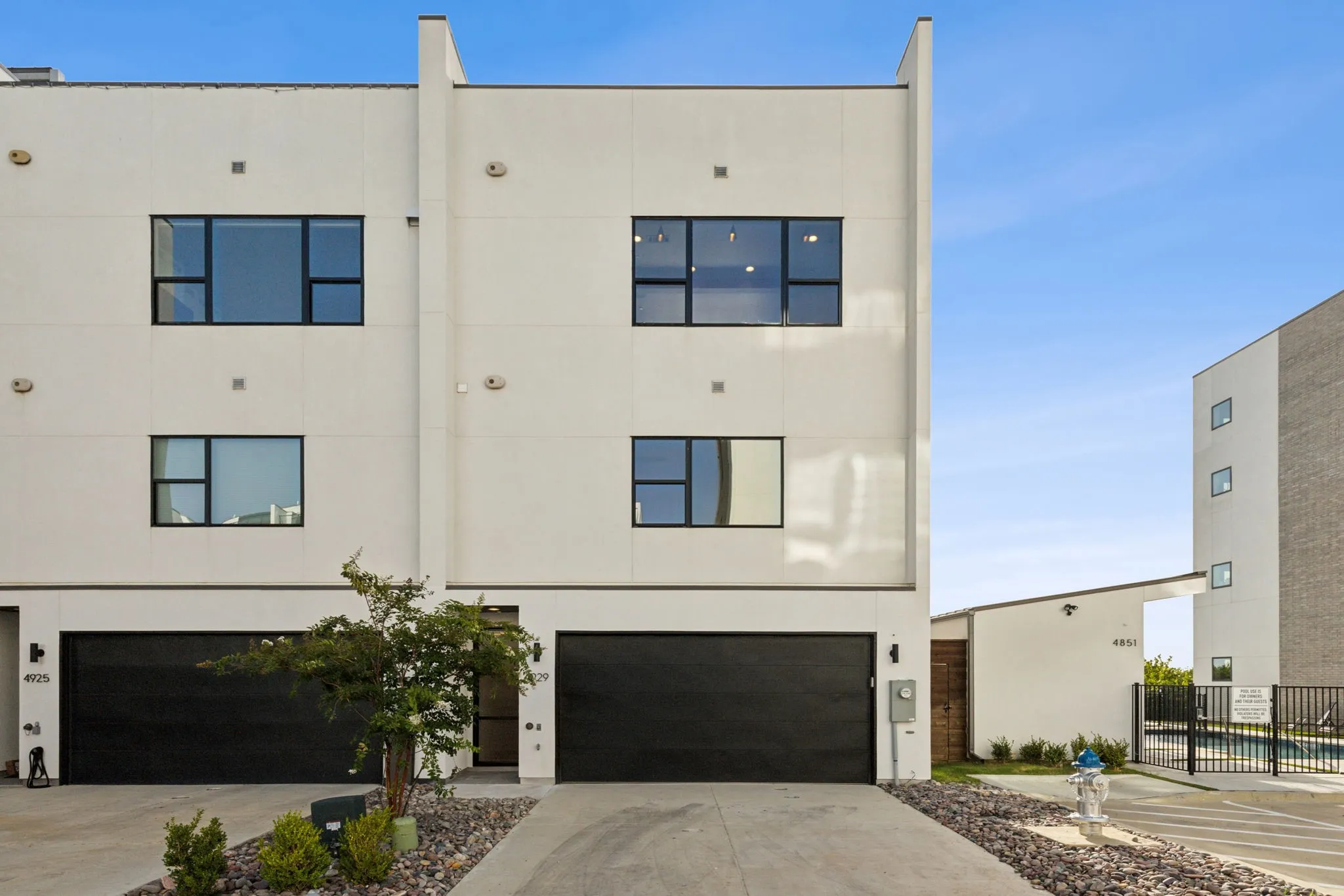 View of front of property featuring a garage, stucco siding, driveway, and fence