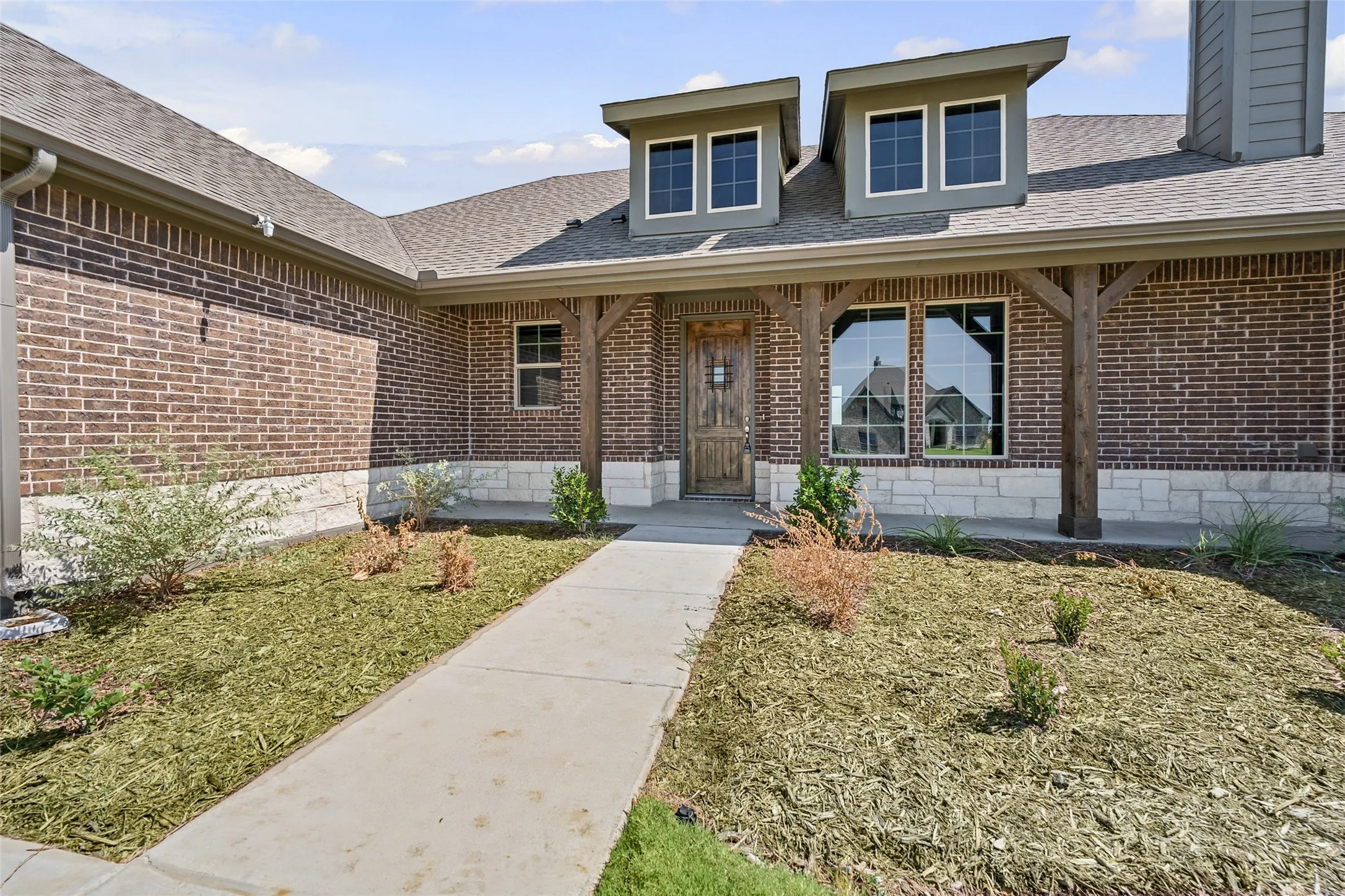 Brick exterior with stone accents, covered entry, and dormer windows