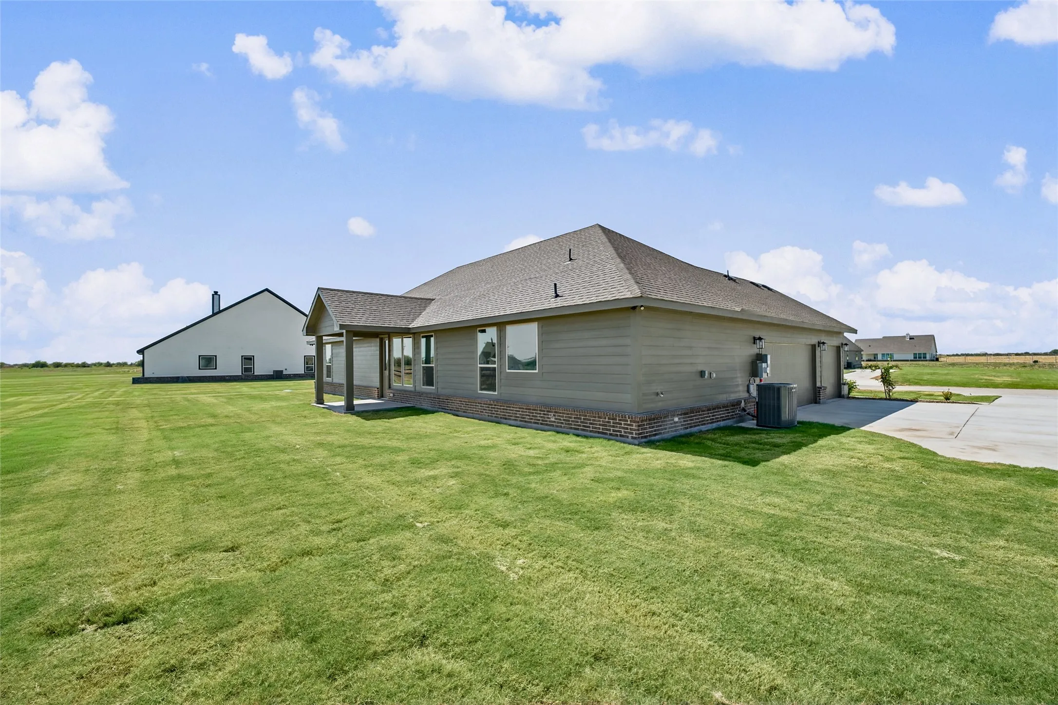 Expansive lawn featuring a concrete patio with a covered porch and a concrete driveway