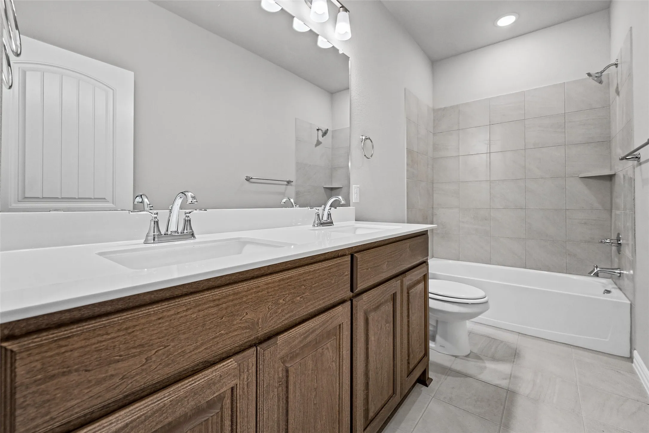 Dual vanity with wood-finish cabinetry, white countertop, and chrome fixtures
