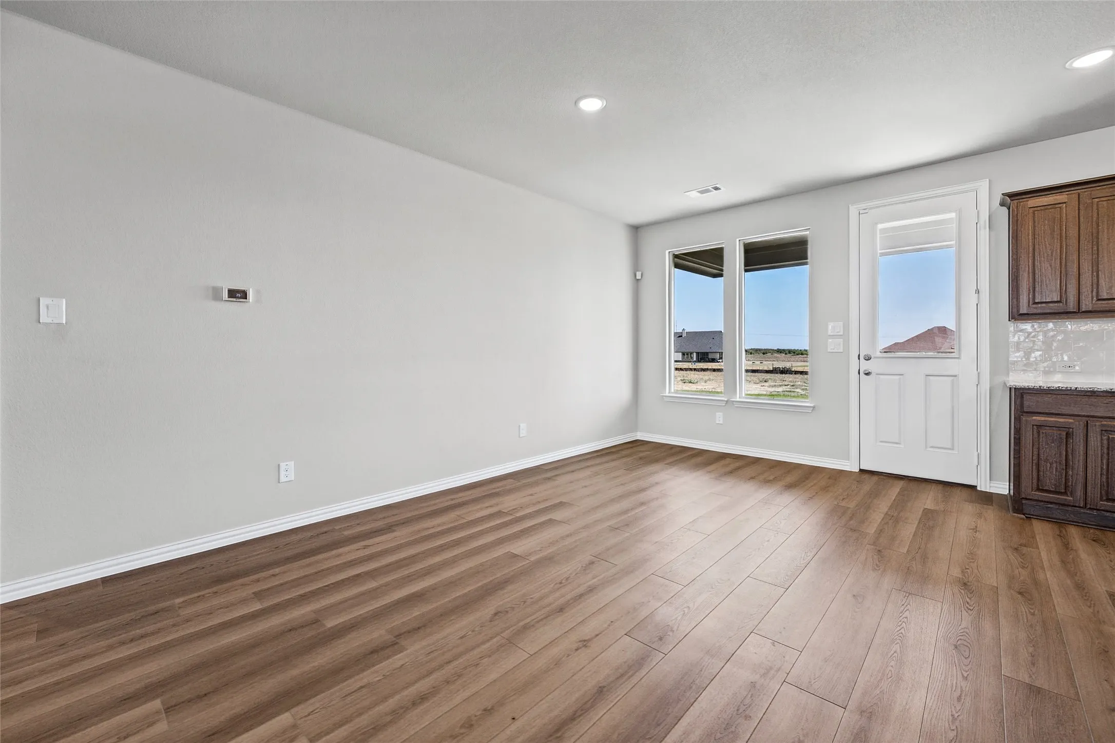 Wood-finish flooring, recessed lighting, and a white paneled door with glass insert