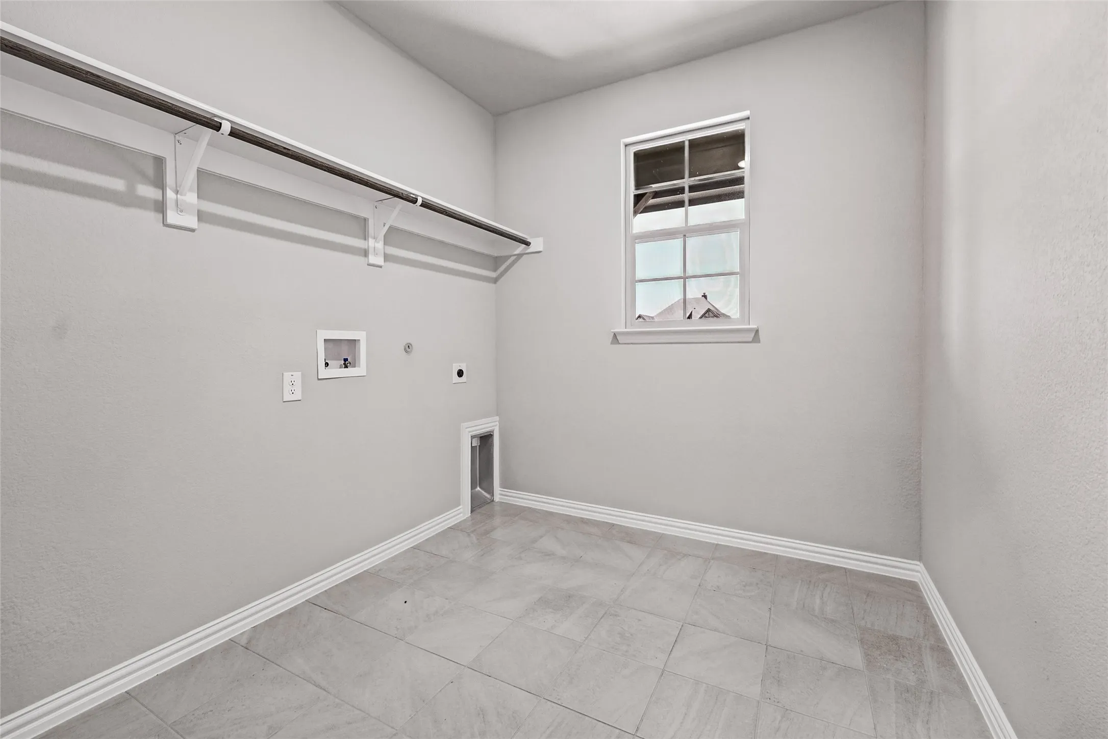 Floor-to-ceiling shelving with hanging rod, single window, wall-mounted outlets, and light-toned tile flooring