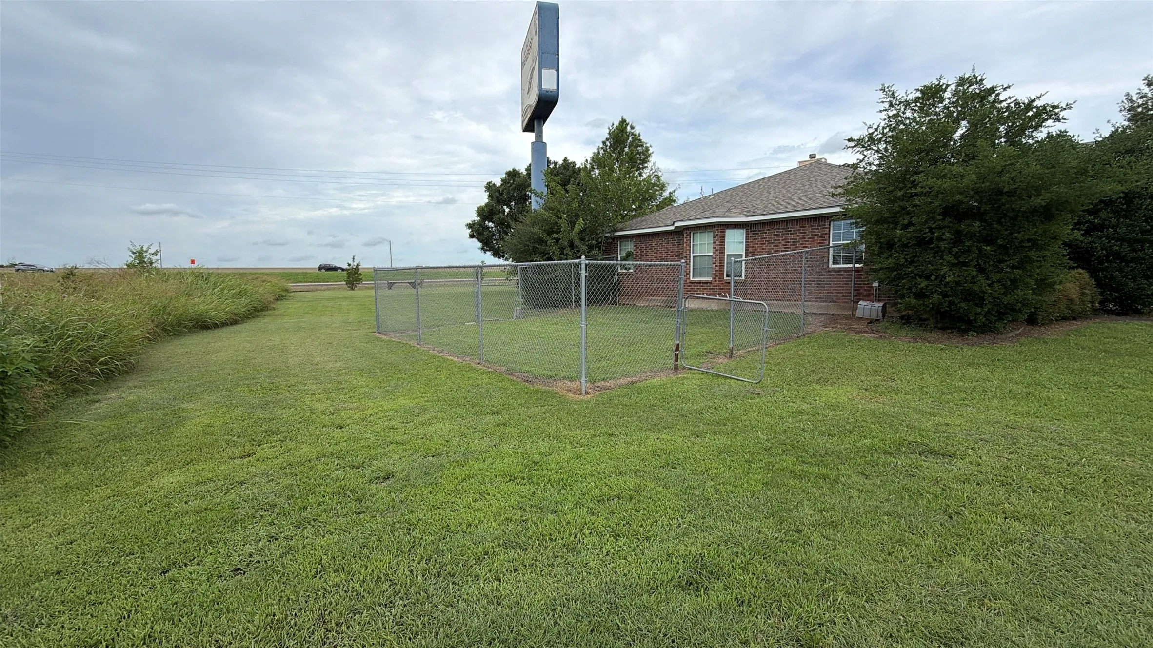 Expansive grass area featuring a chain-link fence enclosure