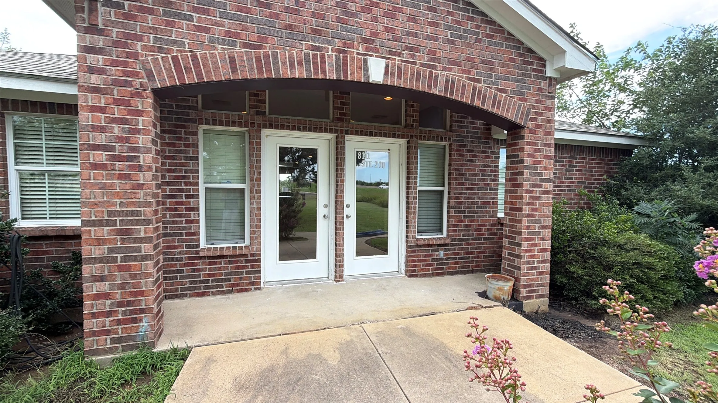 Brick exterior featuring a covered patio with an arched entryway