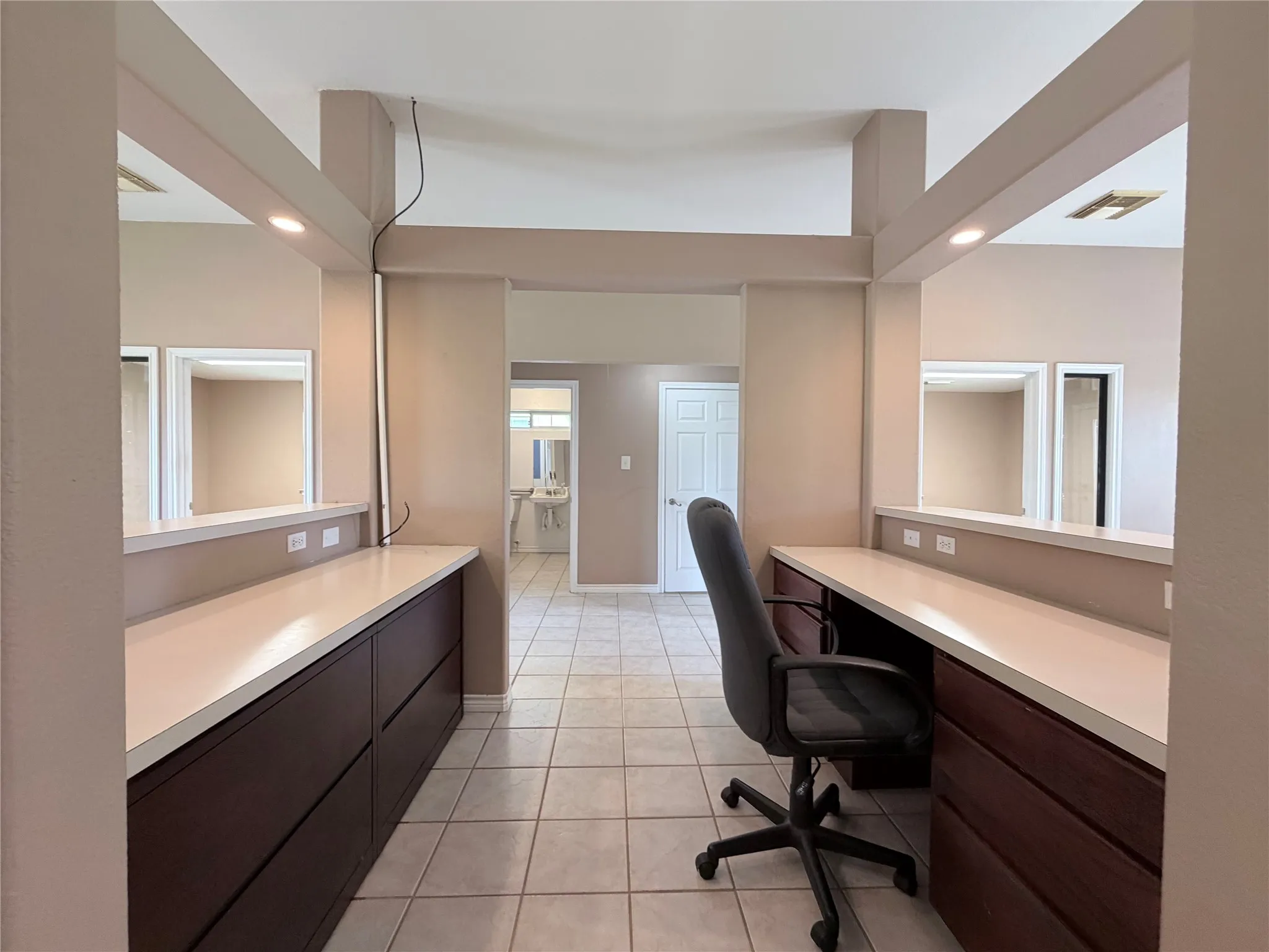Workspace featuring dual built-in dark wood-finish cabinetry, light countertops, and recessed lighting