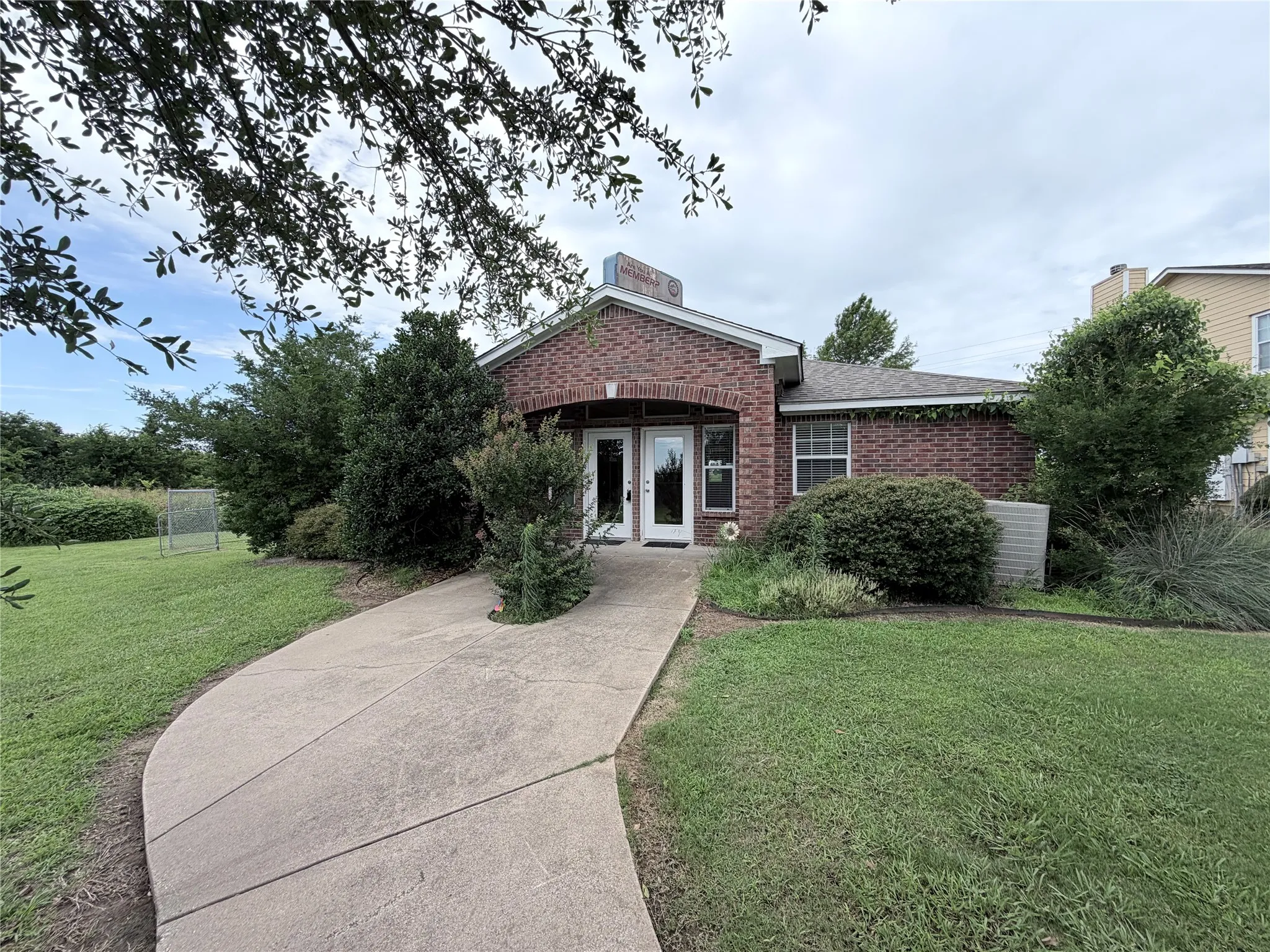 Brick exterior featuring a covered entryway, a white framed window, and a concrete pathway
