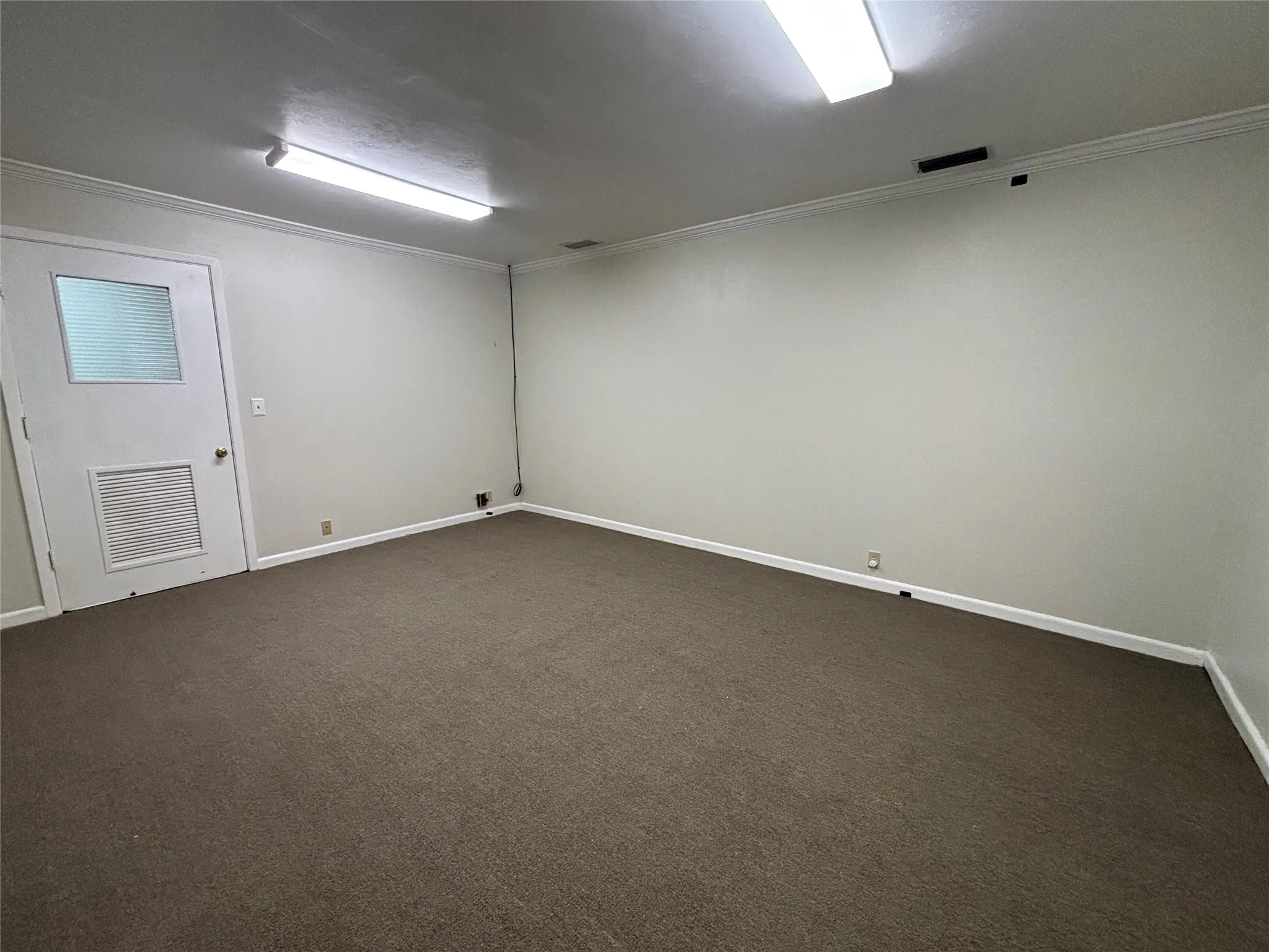 Neutral wall paint, crown molding, brown carpet flooring, white trim, and fluorescent lighting fixtures
