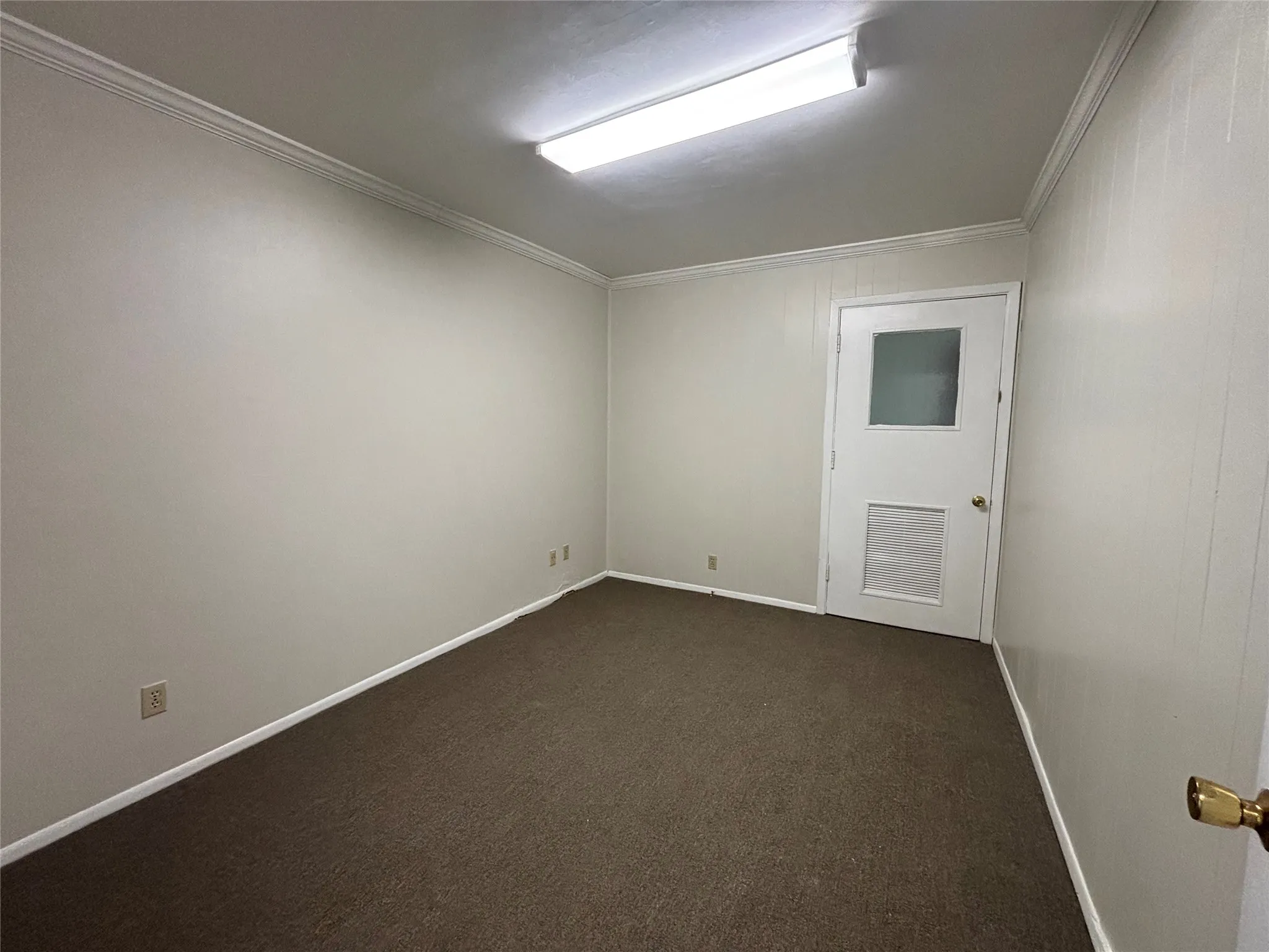 Neutral wall finishes, crown molding, brown carpeting, and a white door with frosted glass
