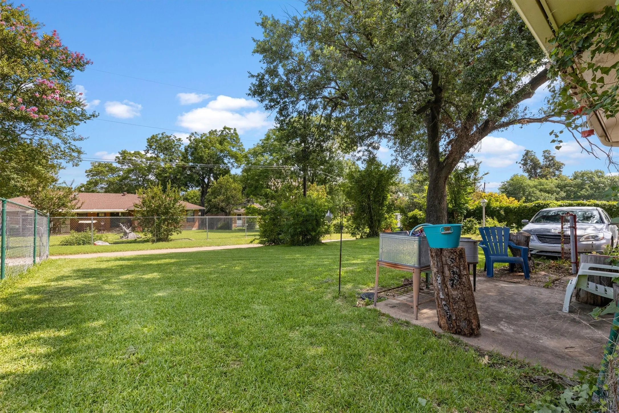 Expansive grassy yard with mature trees and perimeter fencing